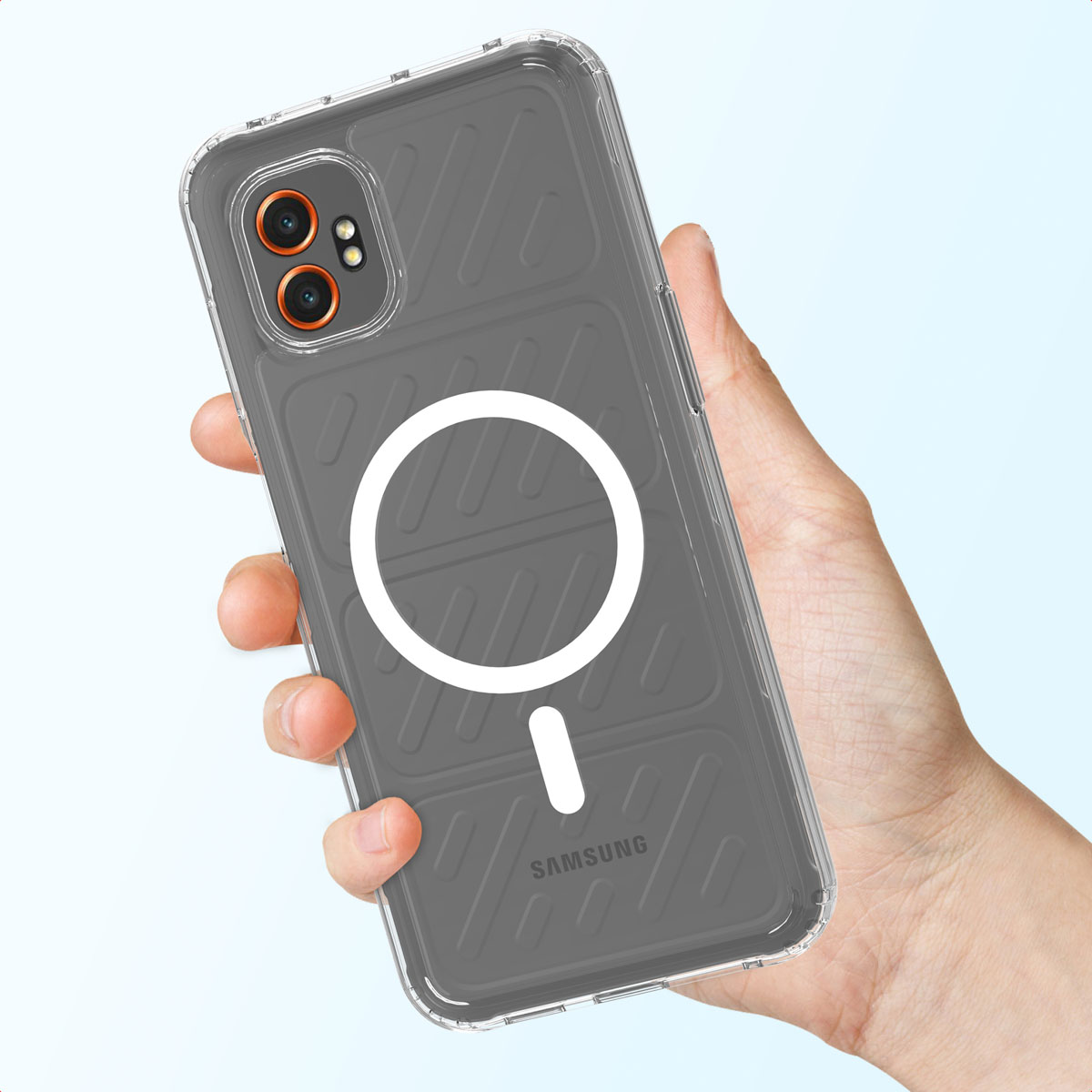Une main tenant une coque de téléphone transparente avec un dos gris, un cercle blanc et un tiret blanc. Le téléphone a des lentilles de caméra orange.