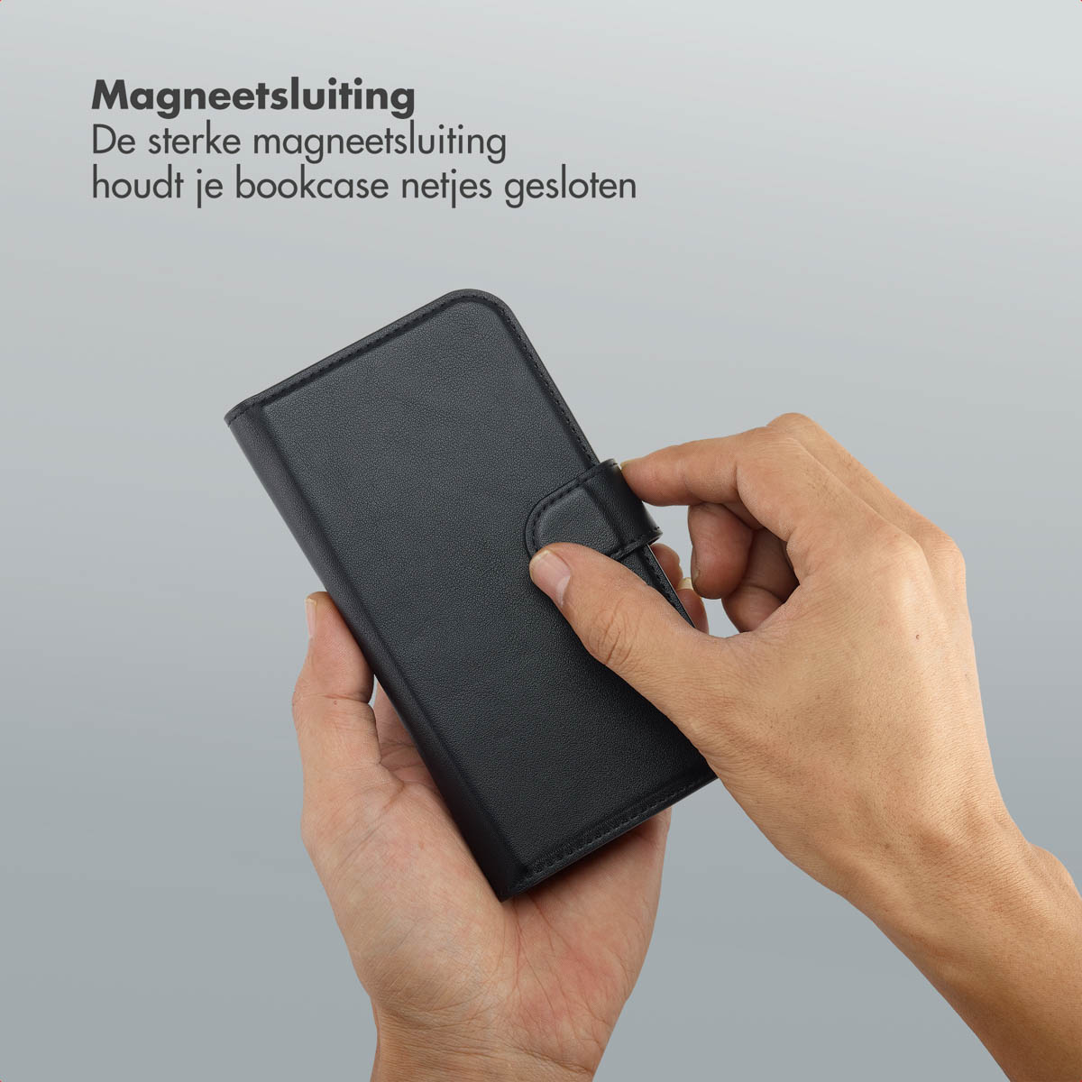 Mains tenant un étui noir avec fermeture magnétique. Texte en néerlandais.