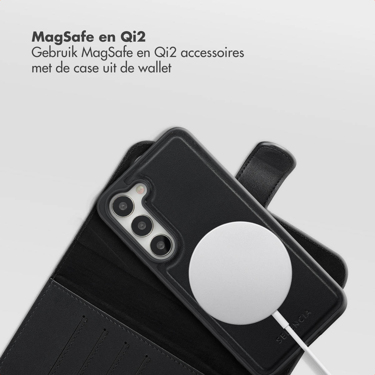 Un téléphone noir dans un étui portefeuille avec un chargeur Qi2 blanc. Le texte en haut dit MagSafe en Qi2.