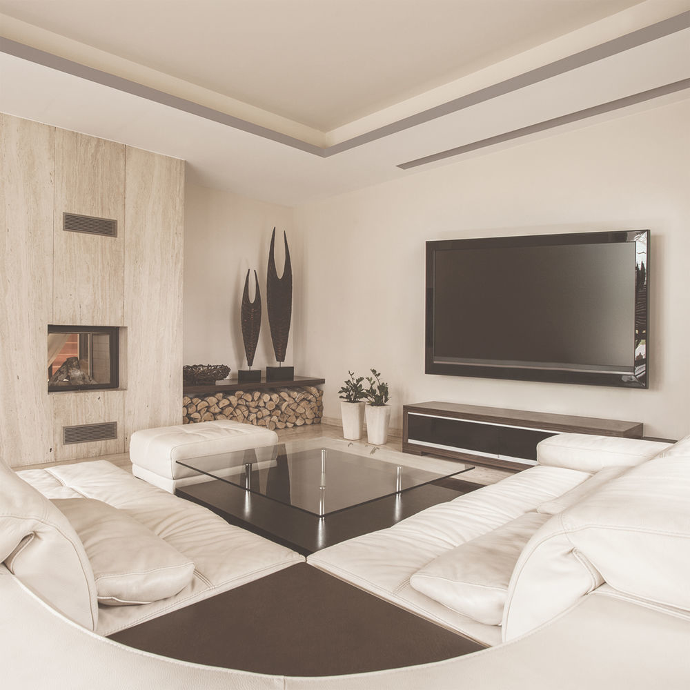 Modern living room with white leather sectional, fireplace, large TV, glass coffee table, and decorative sculptures.