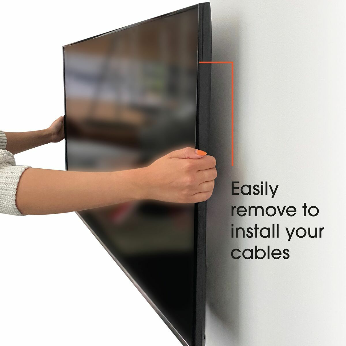 Manos quitando el lateral de un televisor. El televisor está montado en una pared blanca. Texto: 'Retire fácilmente para instalar sus cables'.