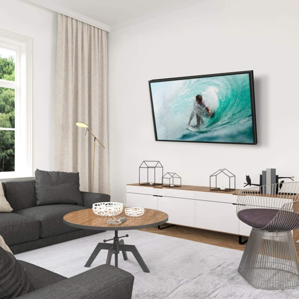 Salon avec une télévision montrant un surfeur. Canapé gris, table basse, chaise et décorations complètent l'espace moderne et aéré.