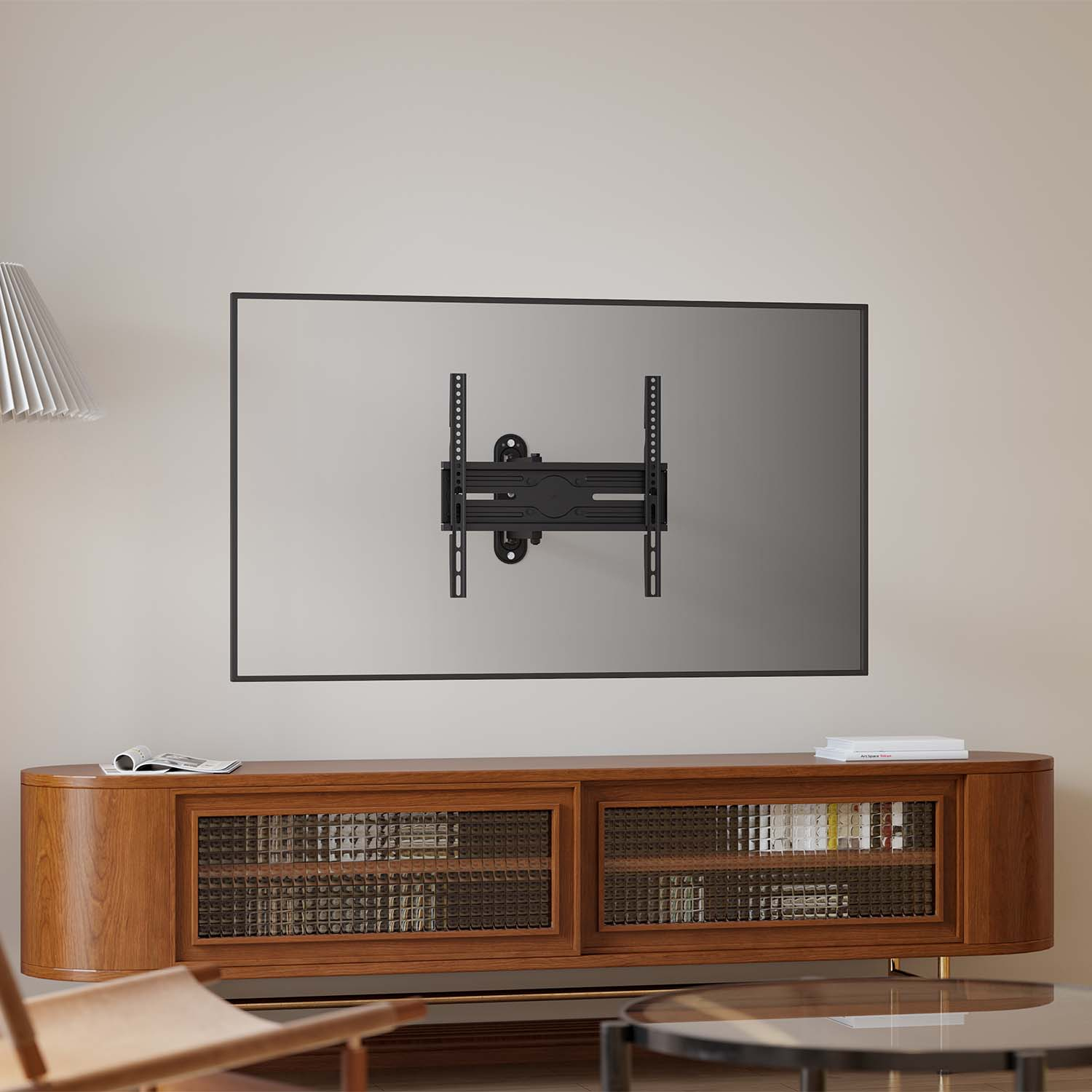 Un soporte de TV negro está fijado a la pared. Debajo, un mueble de madera con puerta de cristal, una mesa y una silla pequeñas.