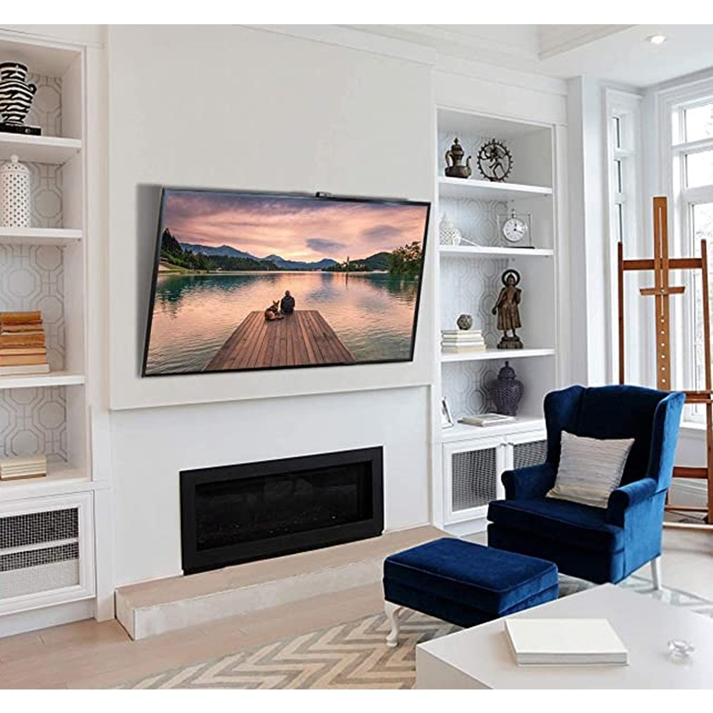 Ein Wohnzimmer mit Fernseher über einem Kamin. Ein blauer Stuhl und eine Ottomane vor einem weißen Tisch. Regale und ein Fenster sind vorhanden.