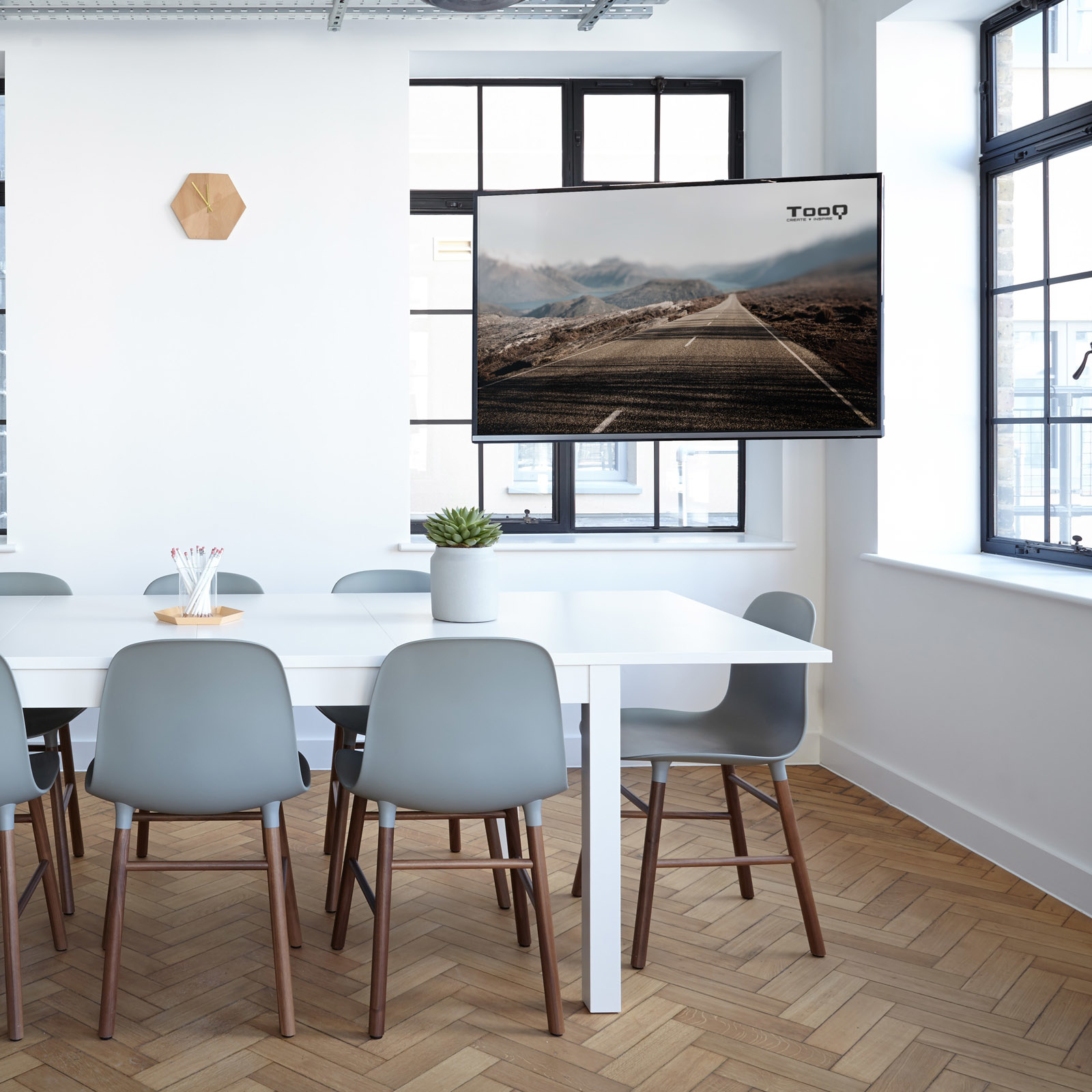 Sala de reuniones con mesa, sillas, una pantalla con una carretera y un reloj de pared.
