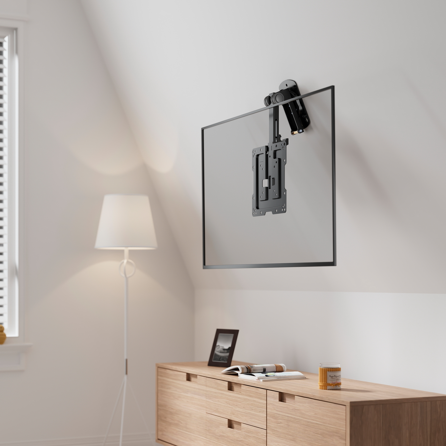 Un televisore montato su una parete bianca. Un mobile in legno e una lampada davanti. Una finestra a sinistra.