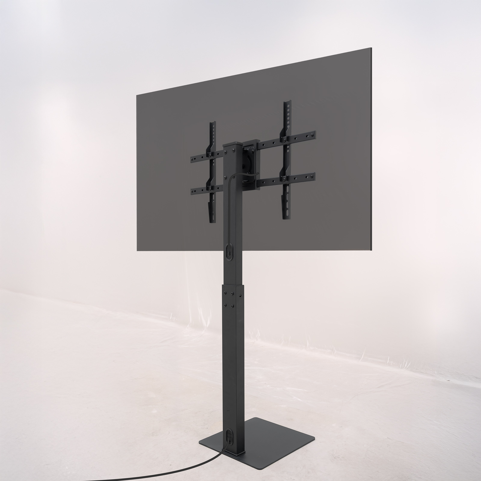 Un televisor negro y rectangular está montado en un soporte negro. El soporte tiene una base cuadrada y un poste vertical.