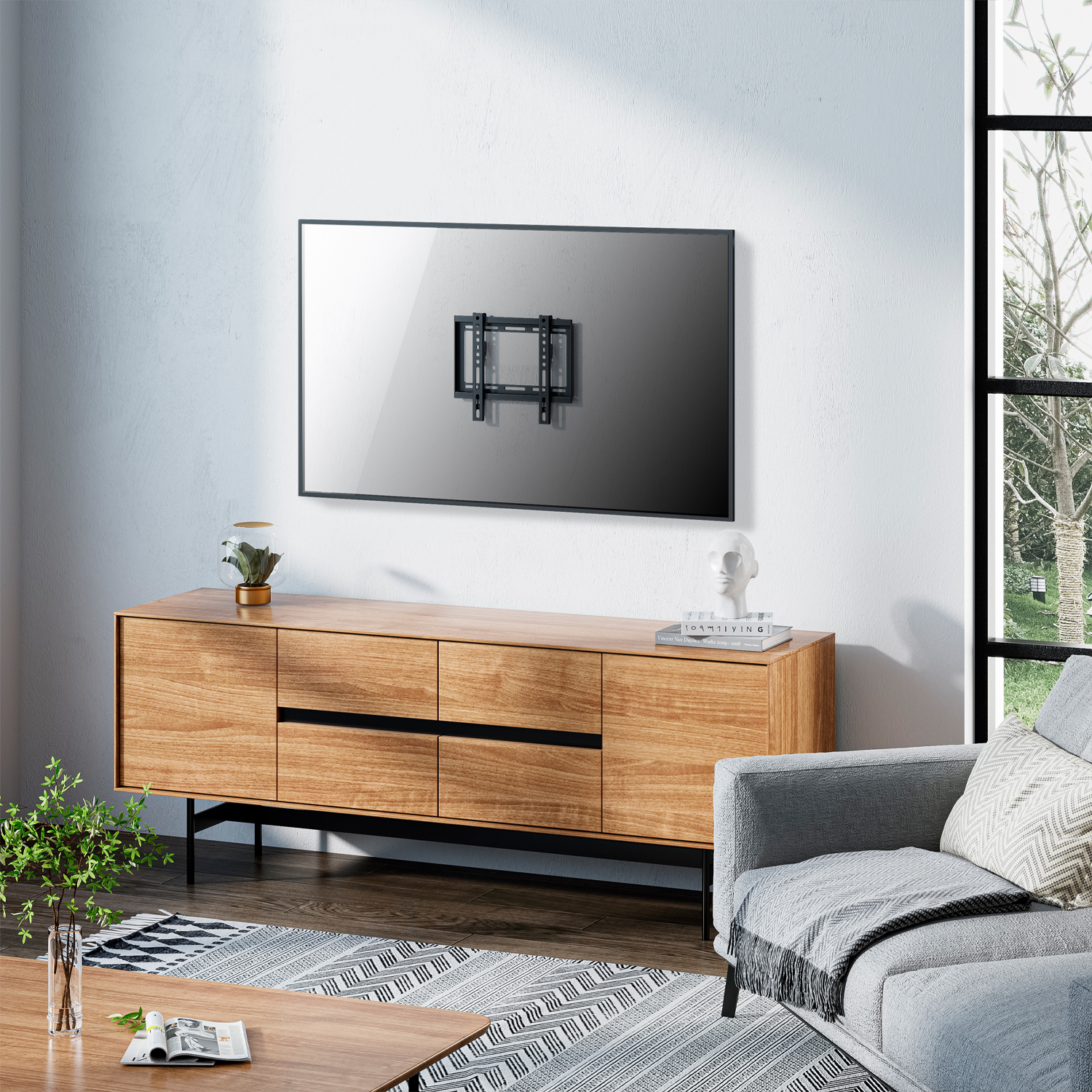Un televisor está montado en una pared blanca. Debajo hay un mueble de madera. Hay un sofá, una ventana y una alfombra en la habitación.