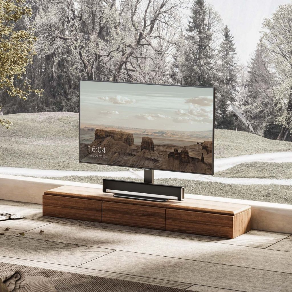 Ein großer Fernseher zeigt eine Landschaft. Er steht auf einem Holzschrank. Der Hintergrund zeigt Bäume und einen bewölkten Himmel.