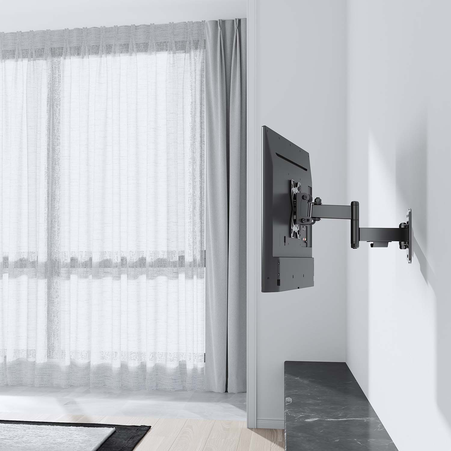Un televisor montado en una pared blanca con un brazo de montaje negro. Cortinas blancas transparentes a la izquierda. Un mueble oscuro abajo.
