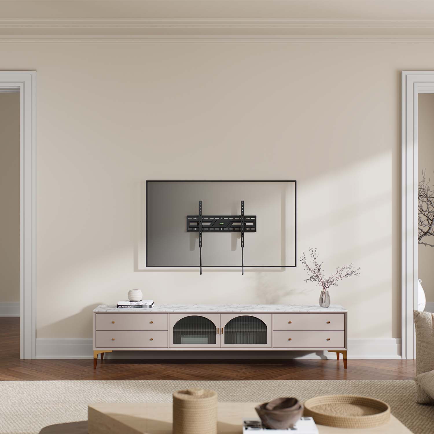 Salón con televisor en la pared, mueble con cajones y jarrón con flores. Hay puertas a ambos lados.