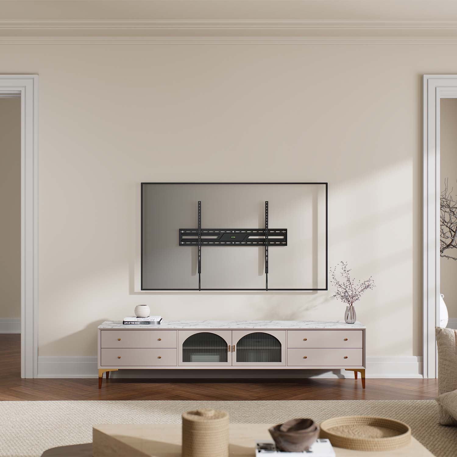 Una sala de estar con un soporte de TV en la pared, un mueble debajo y una mesa de centro enfrente. La habitación tiene paredes claras.