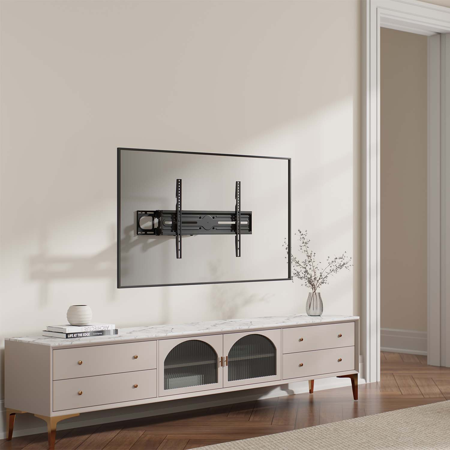 Un supporto TV è installato su un muro. Sotto c'è un mobile con cassetti, porte e un vaso. Il pavimento è in legno. C'è una porta.