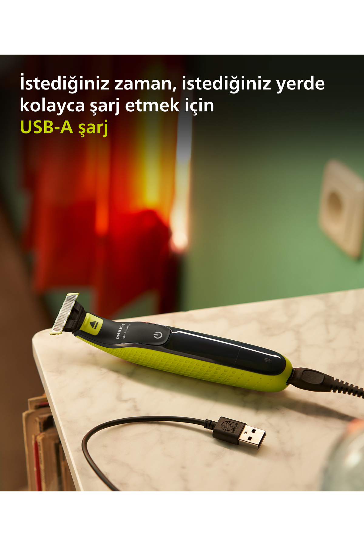 Zielono-czarna trymer Philips OneBlade leży na marmurowej powierzchni. Jest podłączony do kabla do ładowania USB-A.