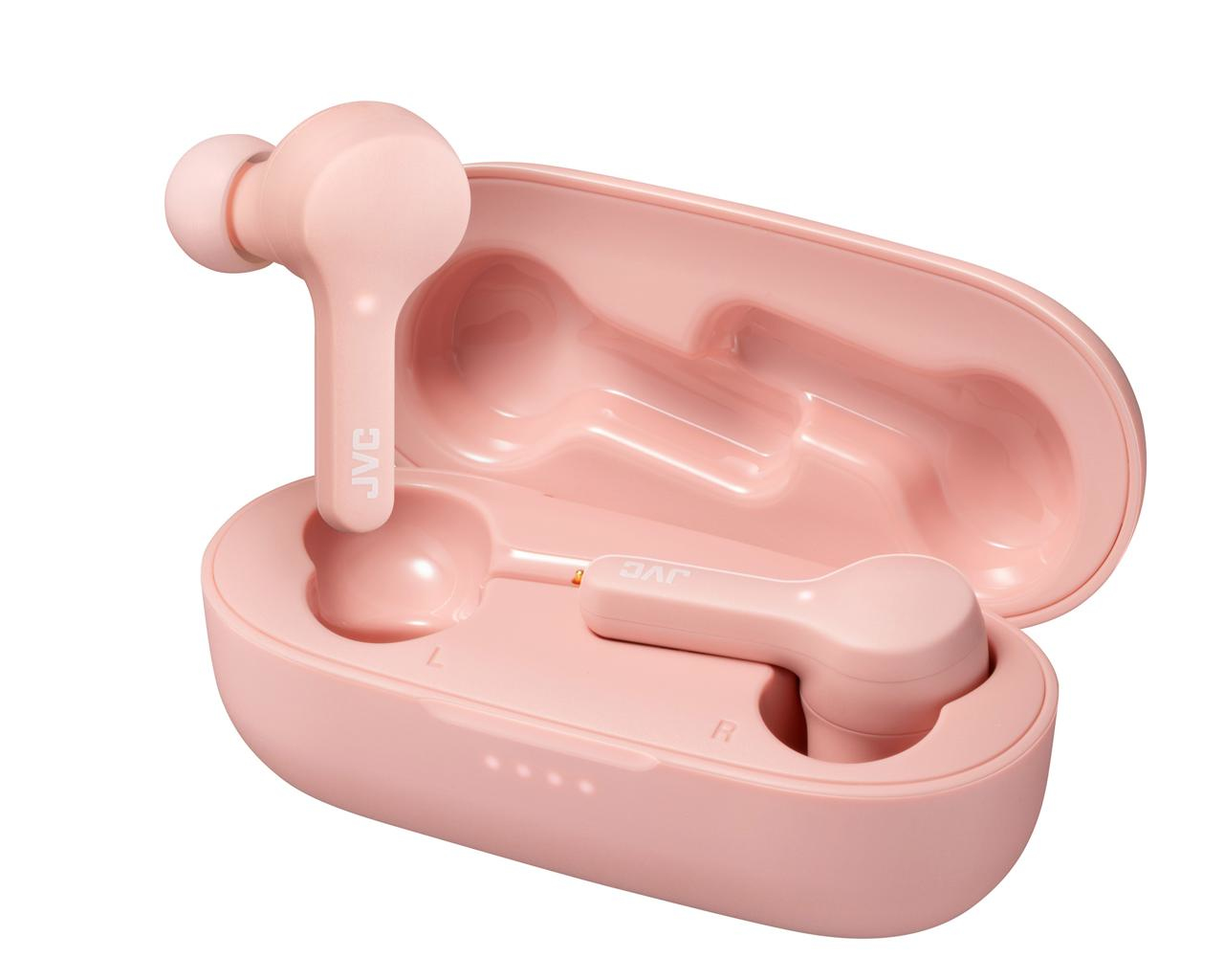 Różowe słuchawki JVC i etui ładujące. Jedna słuchawka na zewnątrz, pozostałe w etui. Etui otwarte.