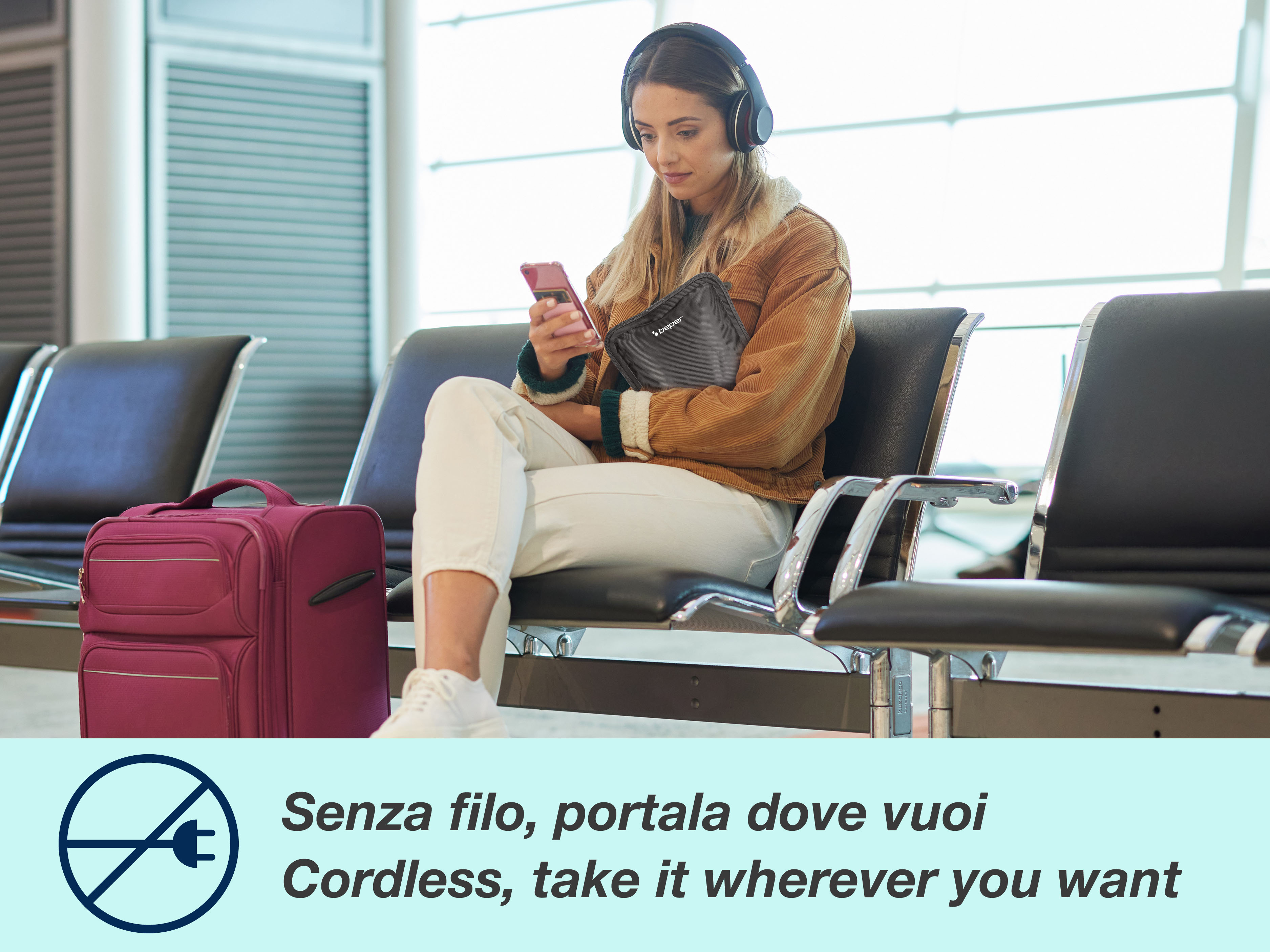 Donna con cuffie in aeroporto usa telefono, tiene borsa. Valigia vicina. Testo: Senza fili, portalo dove vuoi.