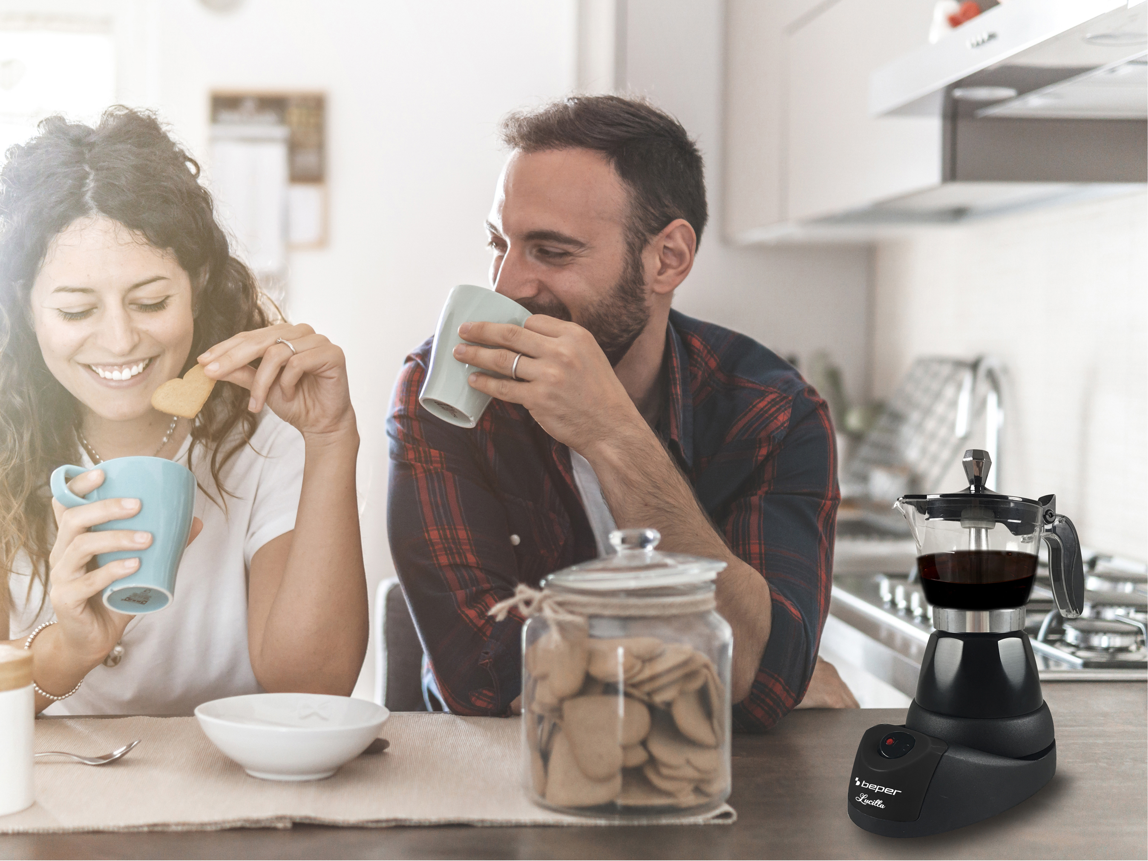Una coppia gusta caffè e biscotti. Una caffettiera è accanto a loro sul tavolo.