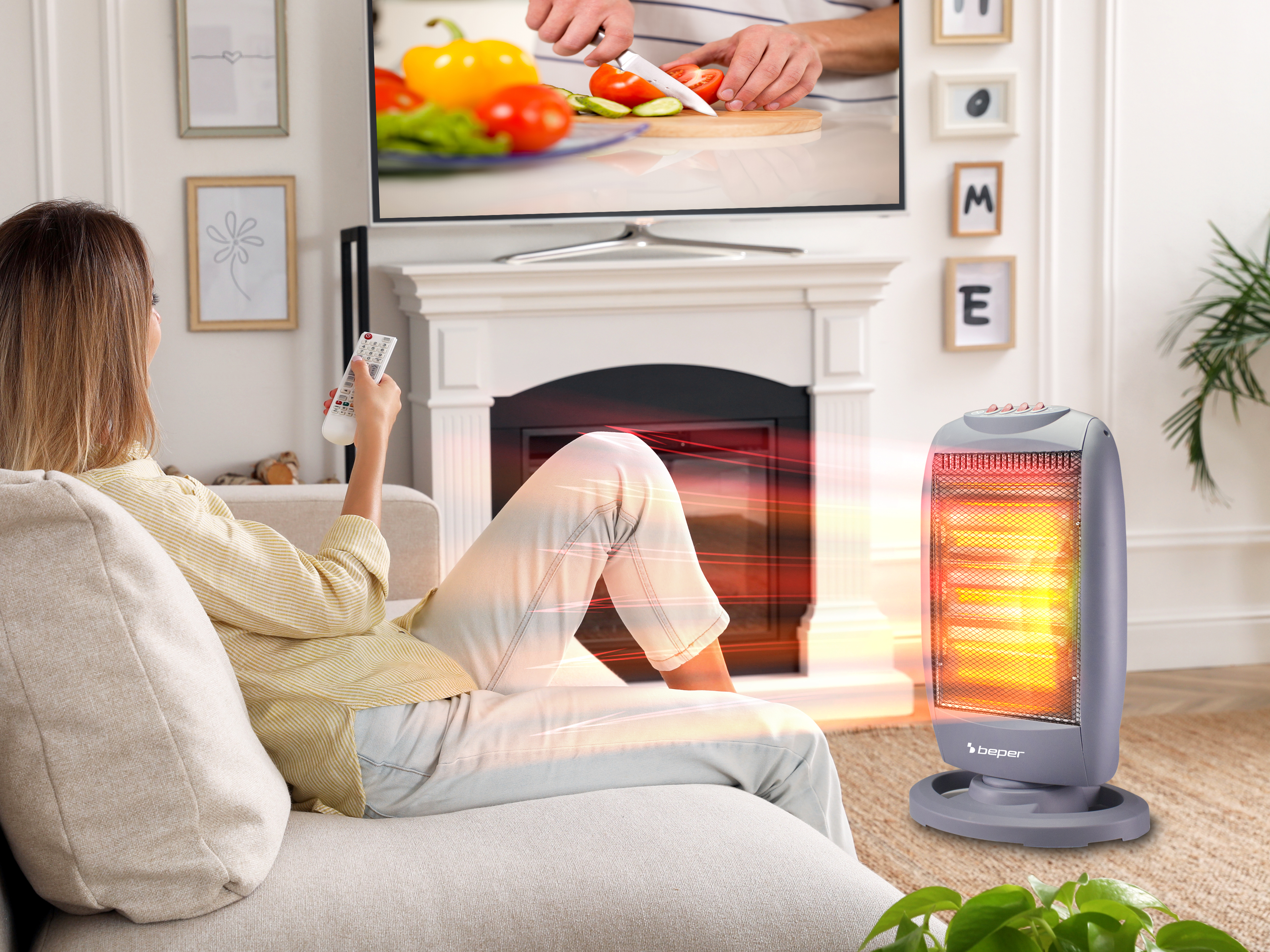 Donna guarda la TV, con telecomando. Un riscaldatore è acceso. La TV mostra cucina. Ambiente accogliente.