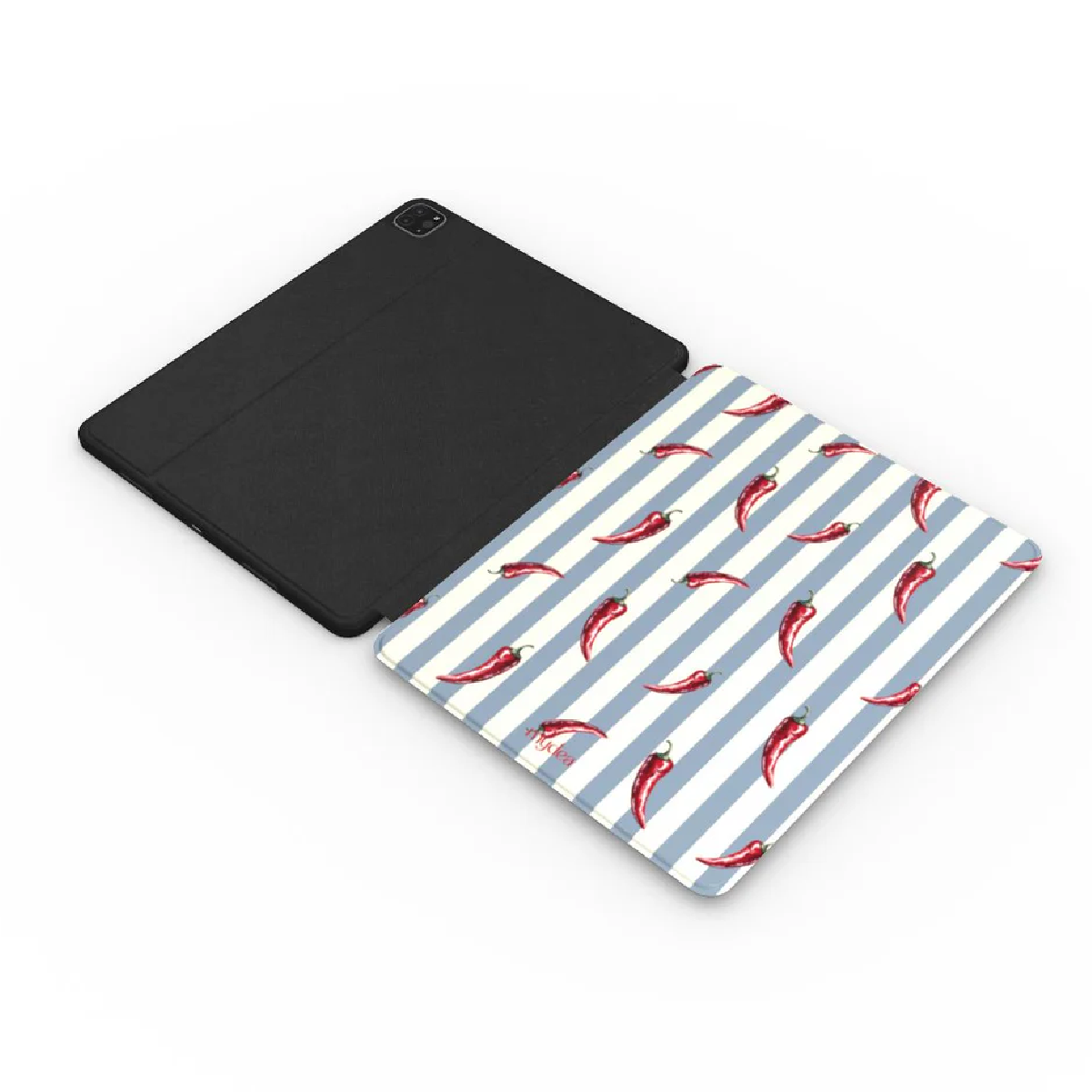 Custodia nera per tablet accanto a un cuscinetto a strisce con peperoncini rossi. Sfondo bianco.