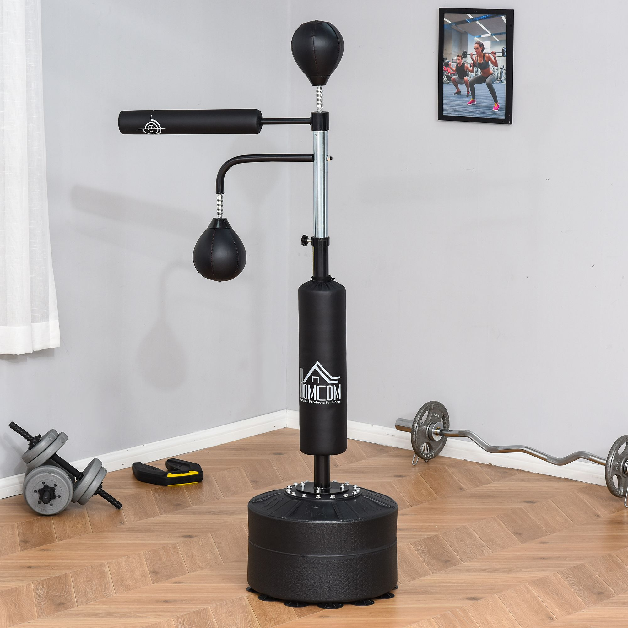 Una estación de entrenamiento de boxeo con saco pesado, pera y mancuernas. Una foto de gente haciendo ejercicio cuelga en la pared.