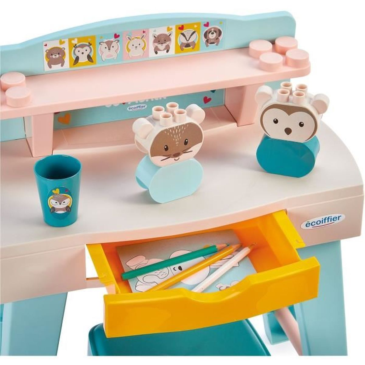 Una scrivania per bambini con blocchi a forma di animali, una tazza e matite nel cassetto. La scrivania ha un ripiano con illustrazioni di animali.