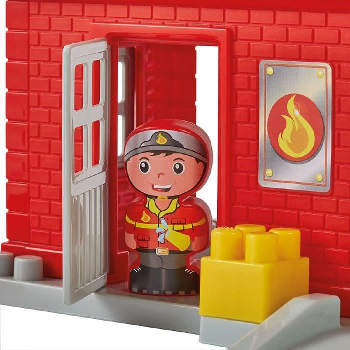 Una caserma dei pompieri giocattolo con una statuetta di pompiere. La caserma è in mattoni rossi, con una porta, una finestra e un simbolo del fuoco.