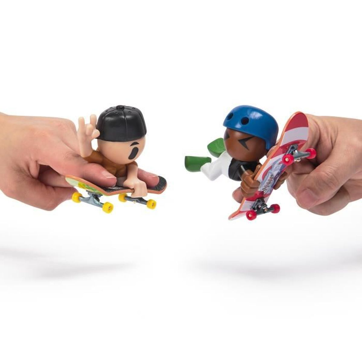 Dwóch zabawkowych skaterów trzymanych w dłoniach. Jeden ma czapkę, drugi niebieski kask. Każdy jeździ na deskorolce.