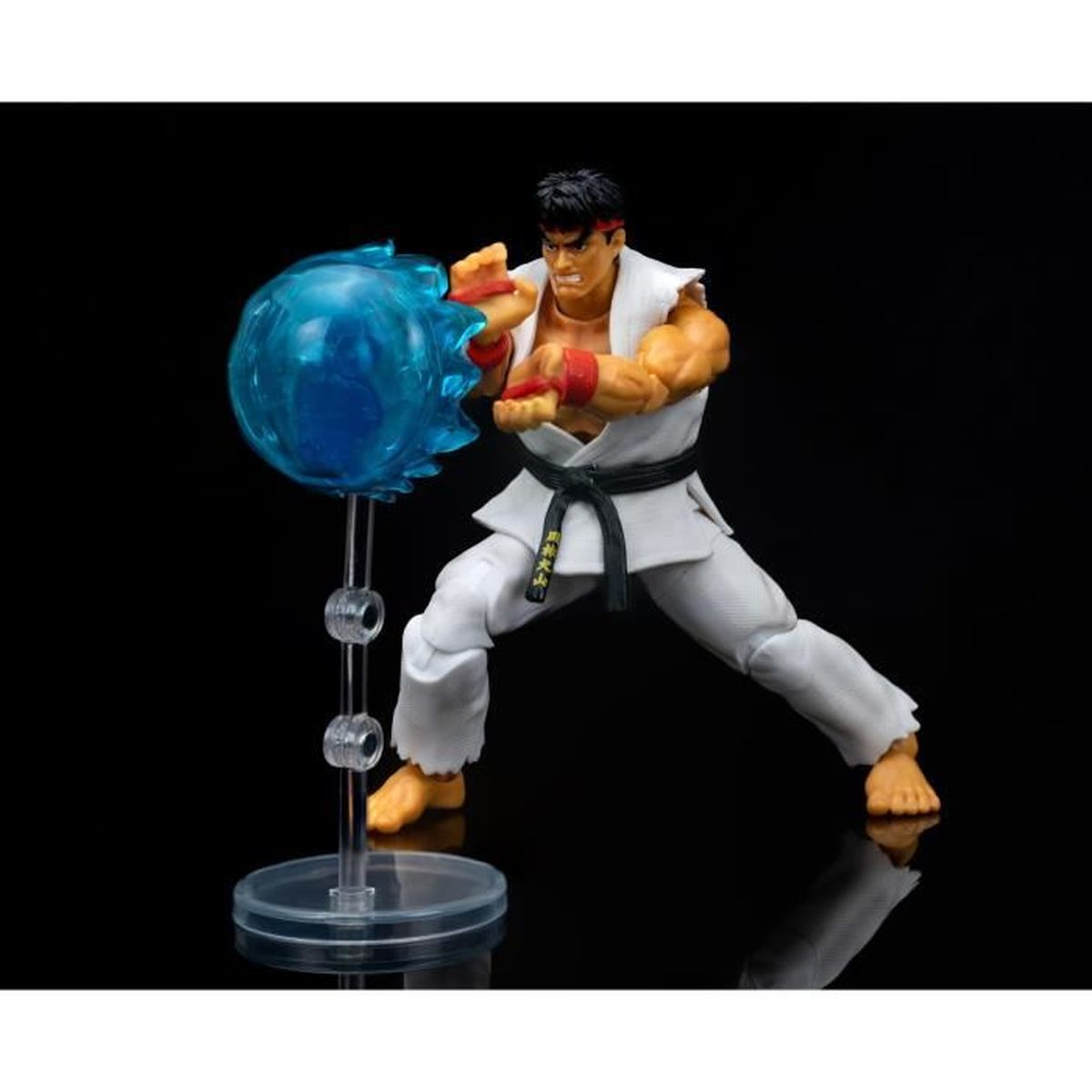 Una action figure di Ryu in posa da combattimento. Un'esplosione di energia blu vicino alla sua mano. Indossa un gi bianco, una cintura nera e una fascia rossa.
