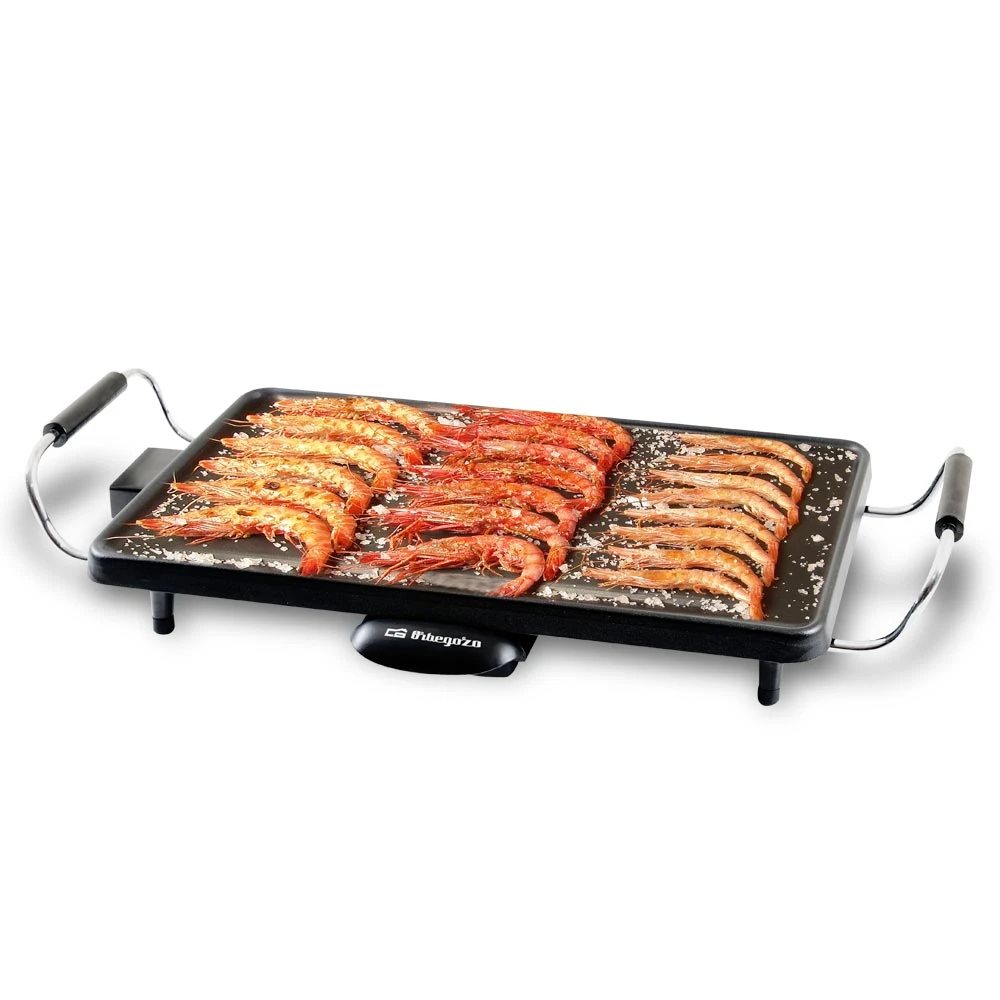 Una parrilla eléctrica rectangular con camarones cocidos. Algunos camarones son naranjas, otros dorados. Sal espolvoreada en la parrilla.