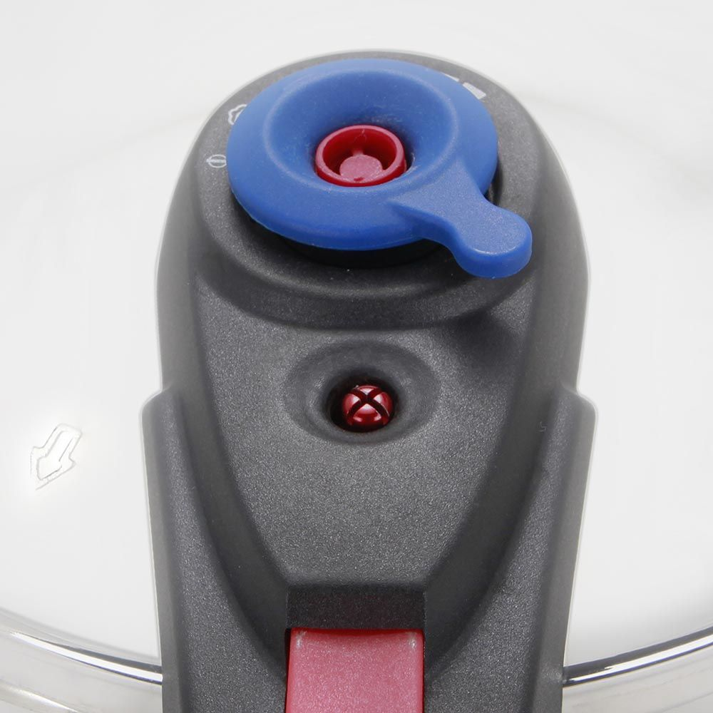 Primer plano de una tapa de olla a presión. Perilla azul con centro rojo, cuerpo gris, botón rojo. Fondo blanco.