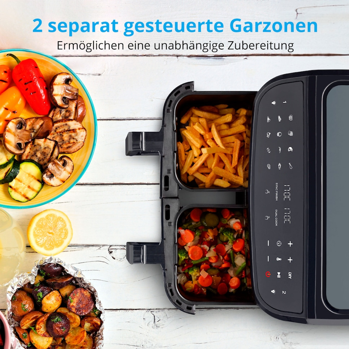 Frytkownica powietrzna z dwiema przegródkami, jedną z frytkami, drugą z warzywami. Grillowane warzywa na talerzu, cytryna i gotowane ziemniaki.