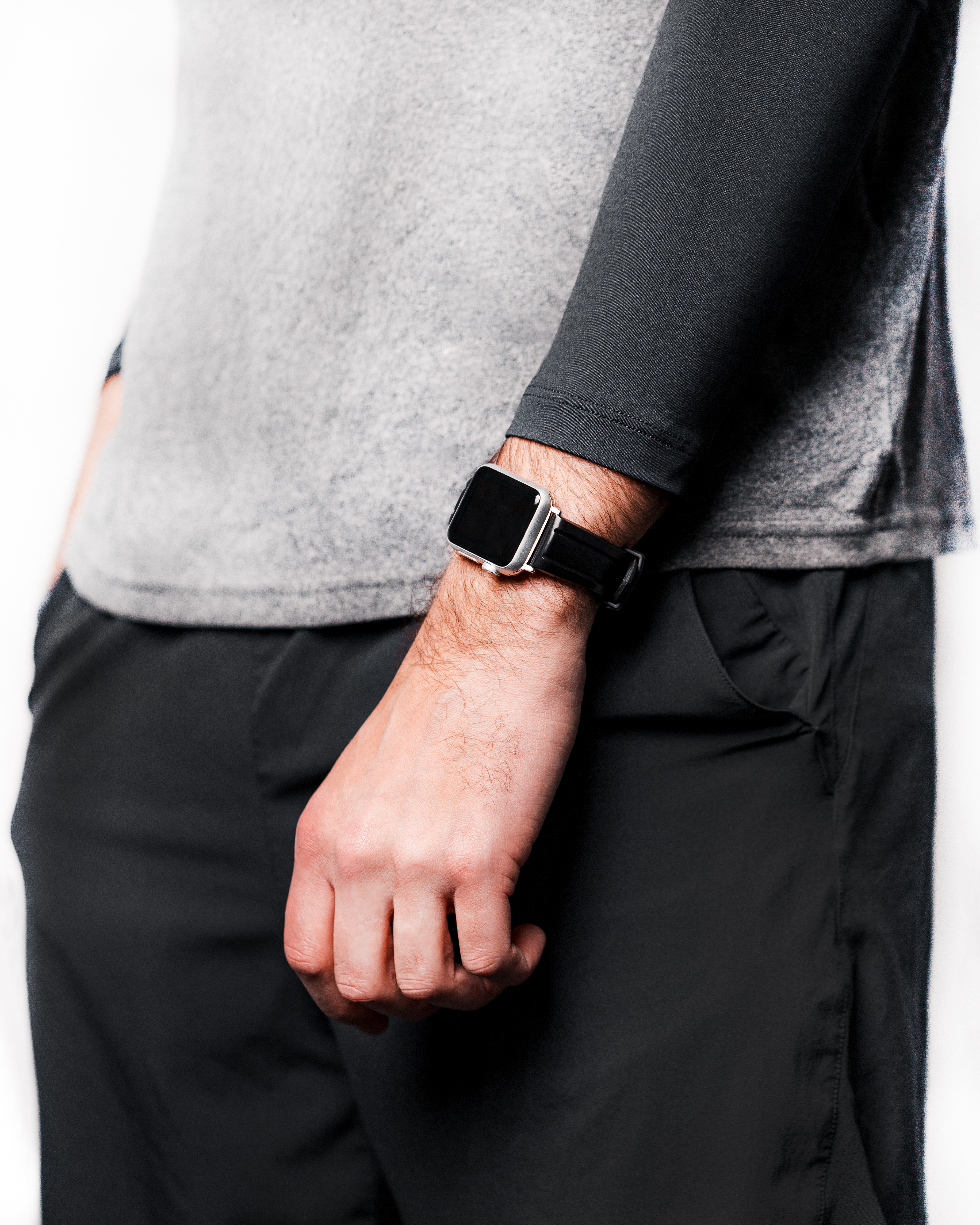 Der Arm einer Person mit Smartwatch. Die Person trägt ein graues Shirt und schwarze Shorts.