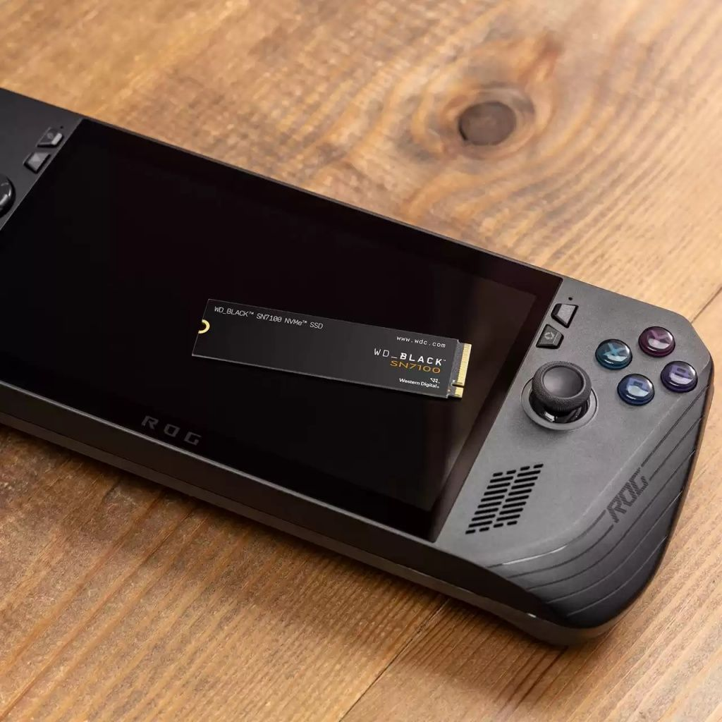 Czarna przenośna konsola do gier z dyskiem SSD WD_BLACK SN7100 na ekranie, umieszczona na drewnianej powierzchni.