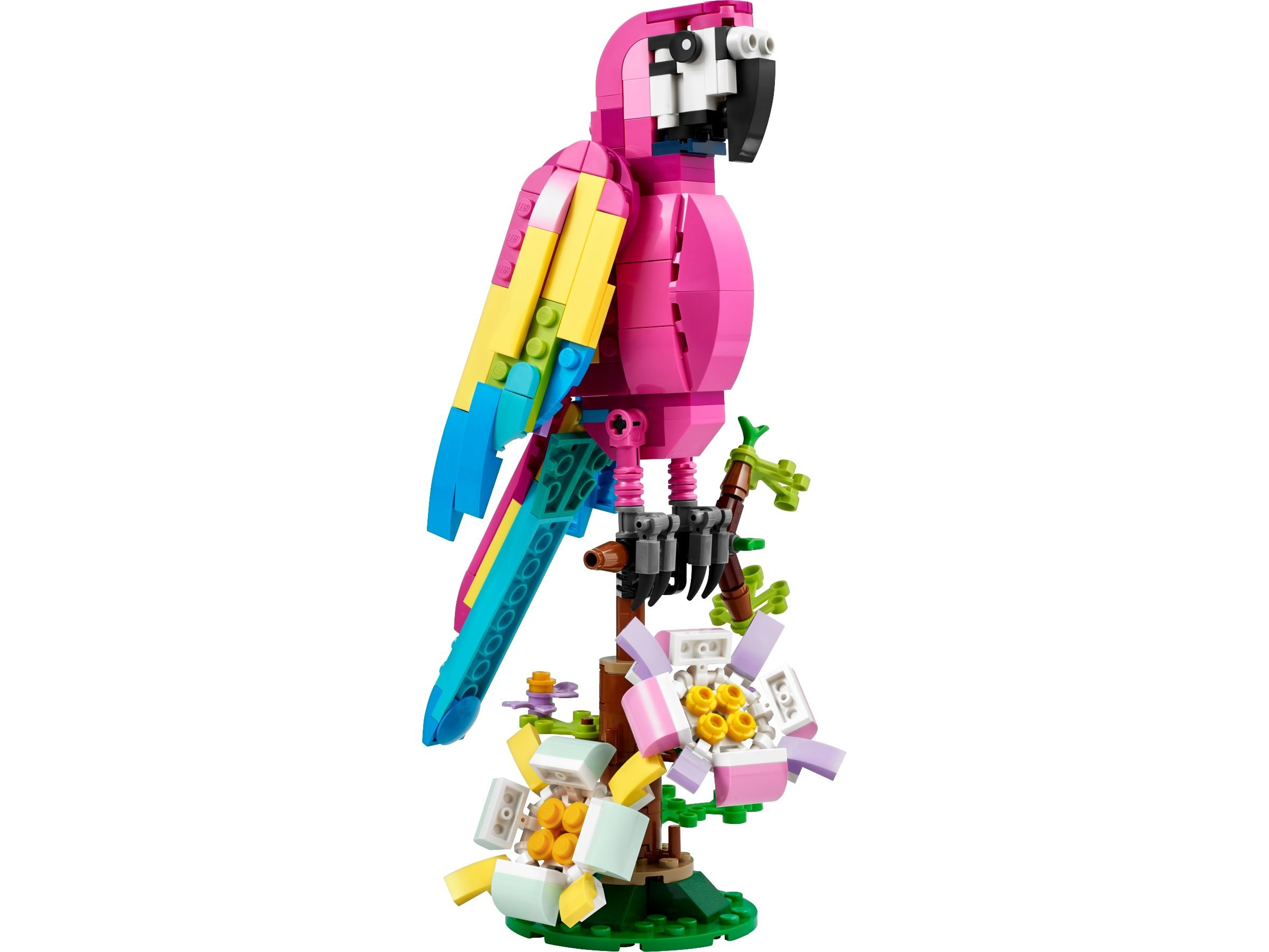 Ein Lego-Papagei sitzt auf einem Baum mit rosa, gelben und blauen Flügeln. Blumen und Blätter sind am Boden.