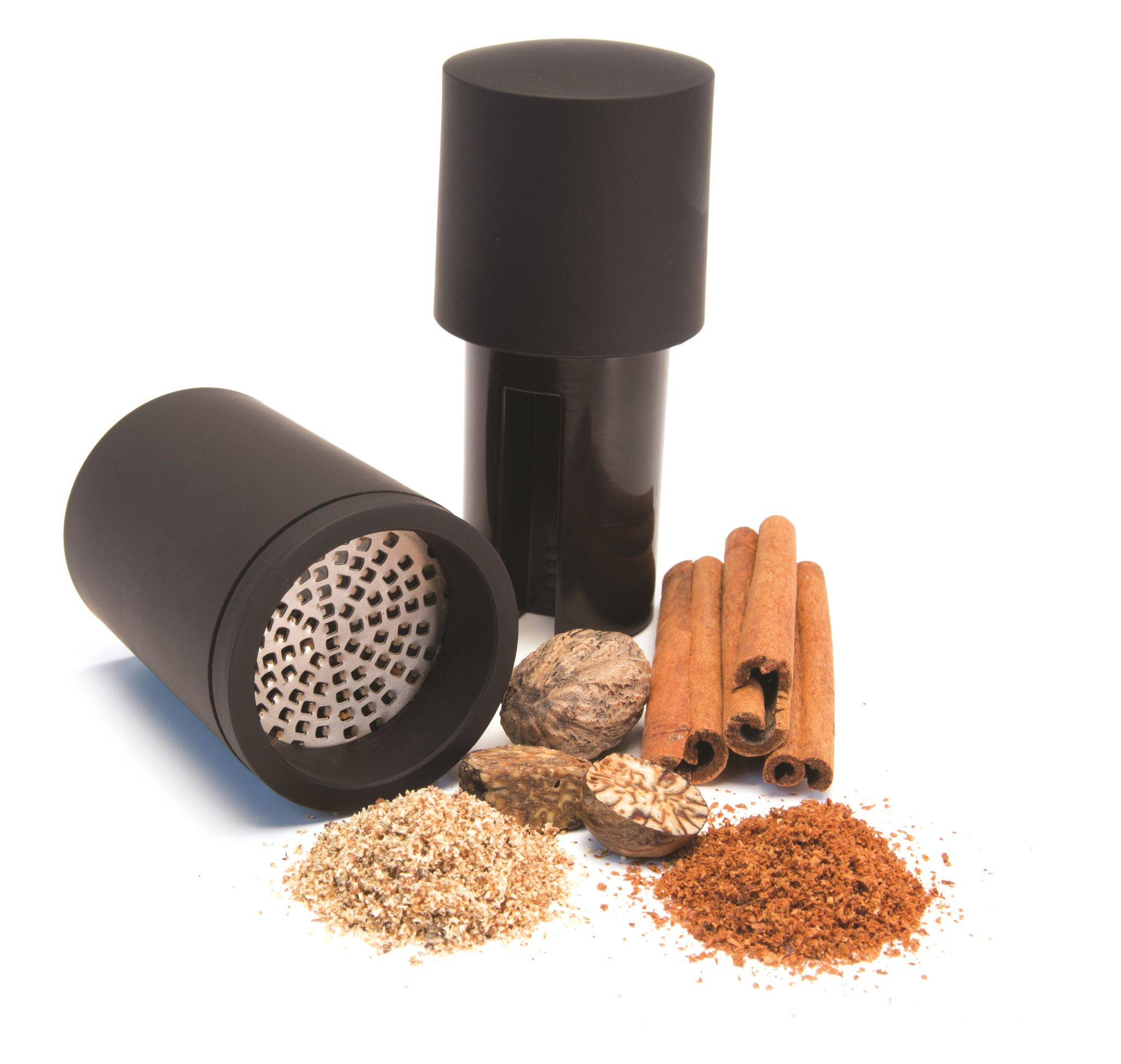 Schwarze Gewürzmühle mit Muskatnüssen, Zimtstangen und gemahlenen Gewürzen auf weißem Hintergrund.