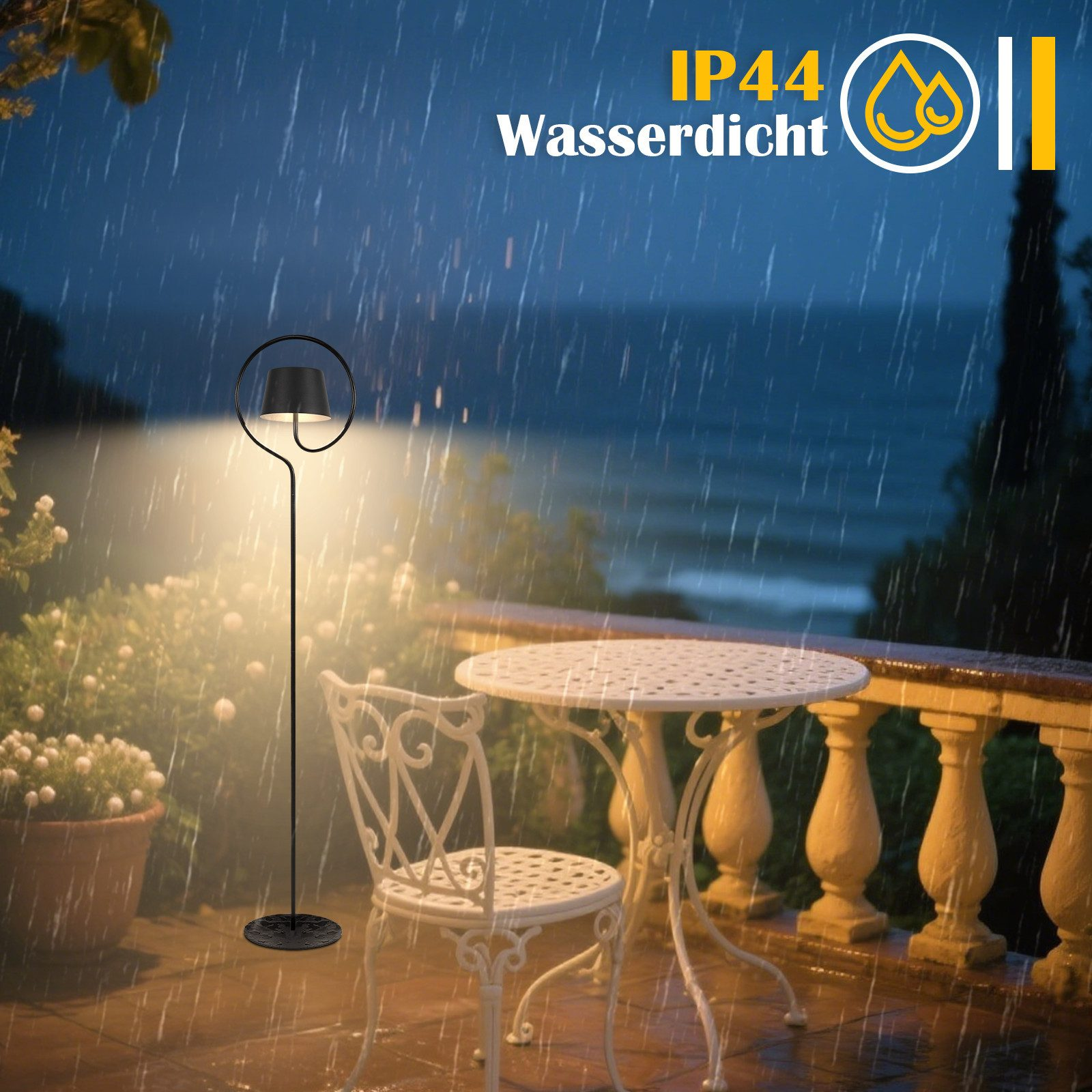 Scena esterna piovosa con lampada, tavolo, sedia e vista mare. La lampada illumina tavolo e sedia. Testo 'IP44 Wasserdicht' visibile.