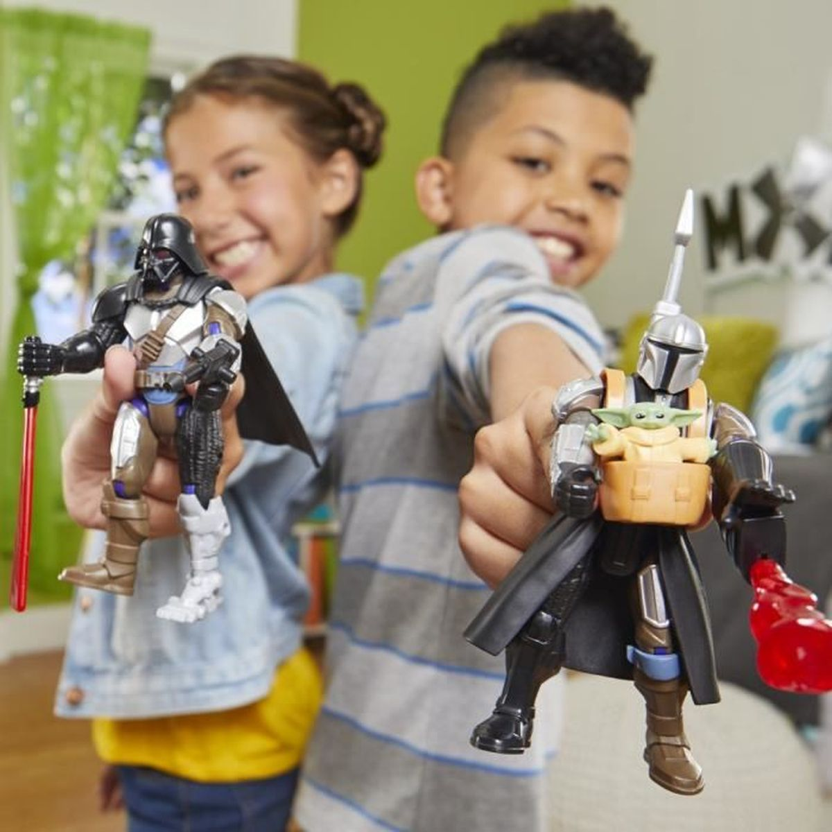 Zwei lächelnde Kinder halten Star Wars-Actionfiguren: Darth Vader mit einem roten Lichtschwert und The Mandalorian mit Grogu.