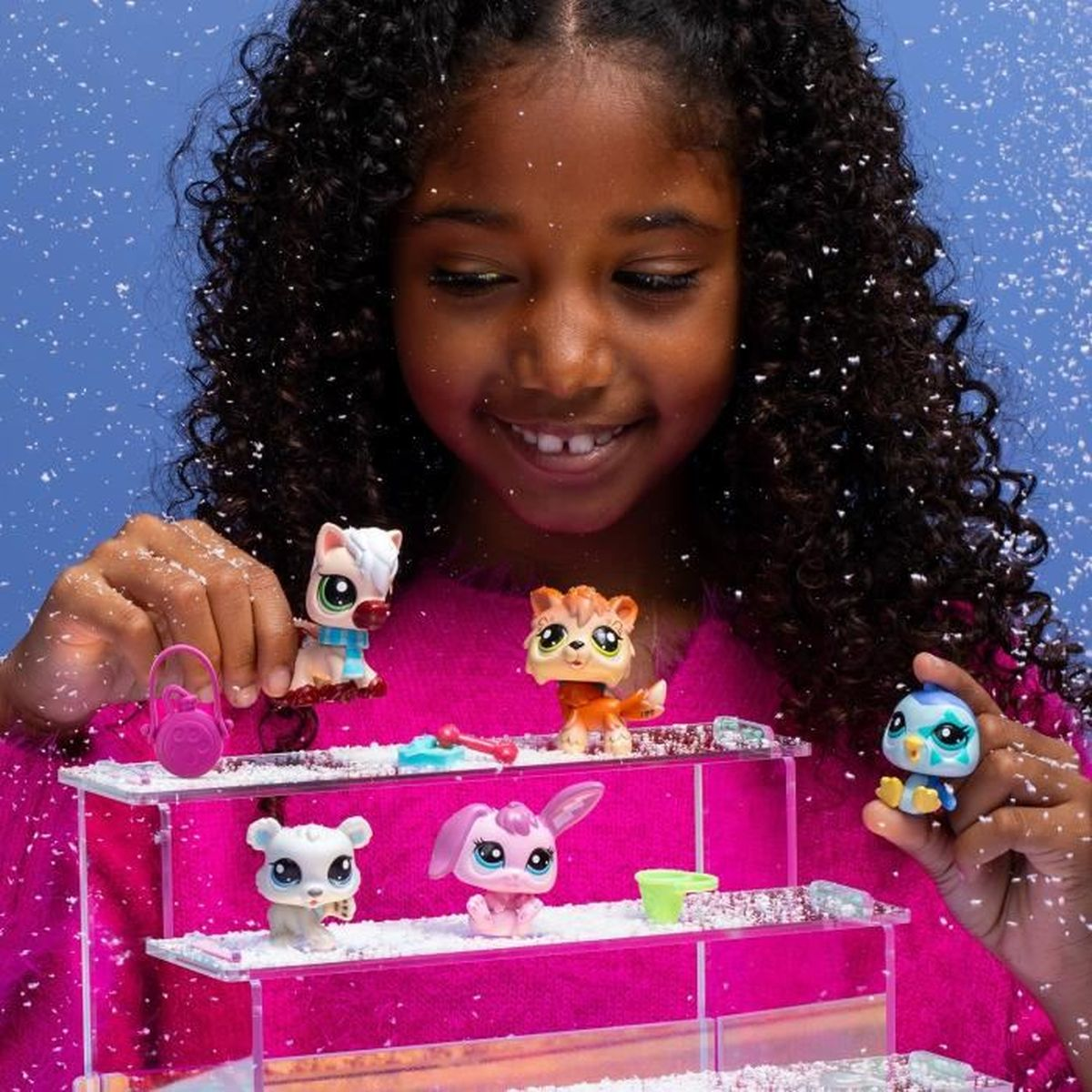 Ein lächelndes Mädchen hält Spielzeugtiere auf Regalen. Ein Pferd, eine Katze, ein Hase, ein Bär und ein Vogel werden in einer schneebedeckten Umgebung ausgestellt.