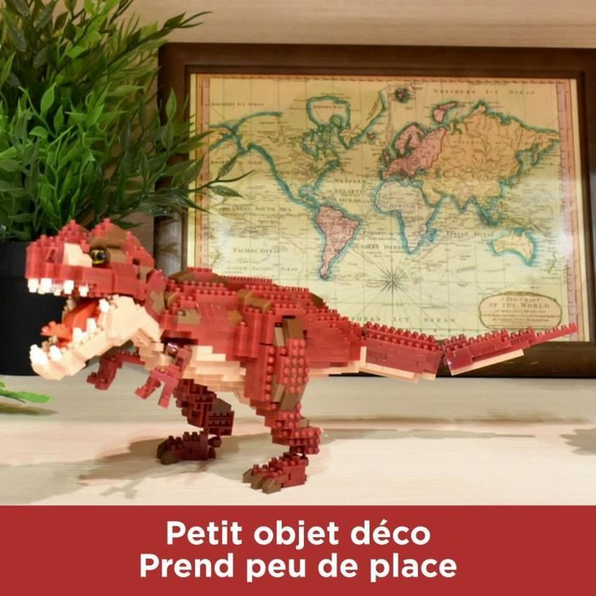 Ein roter Lego-Dinosaurier steht vor einer gerahmten Weltkarte. Grüne Pflanze im Hintergrund. Text unten: 'Petit objet déco'.