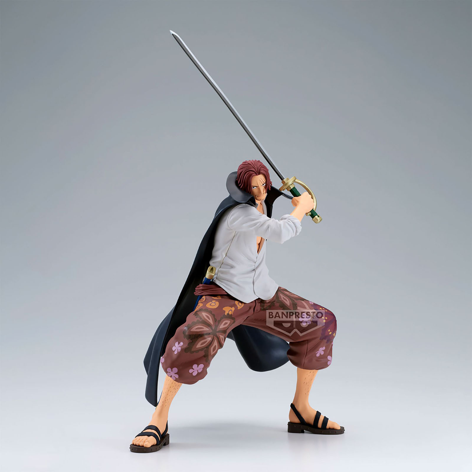 Figur eines Mannes mit roten Haaren, der ein Schwert hält. Er trägt ein weißes Hemd, braune Hose, schwarze Sandalen und einen schwarzen Umhang.