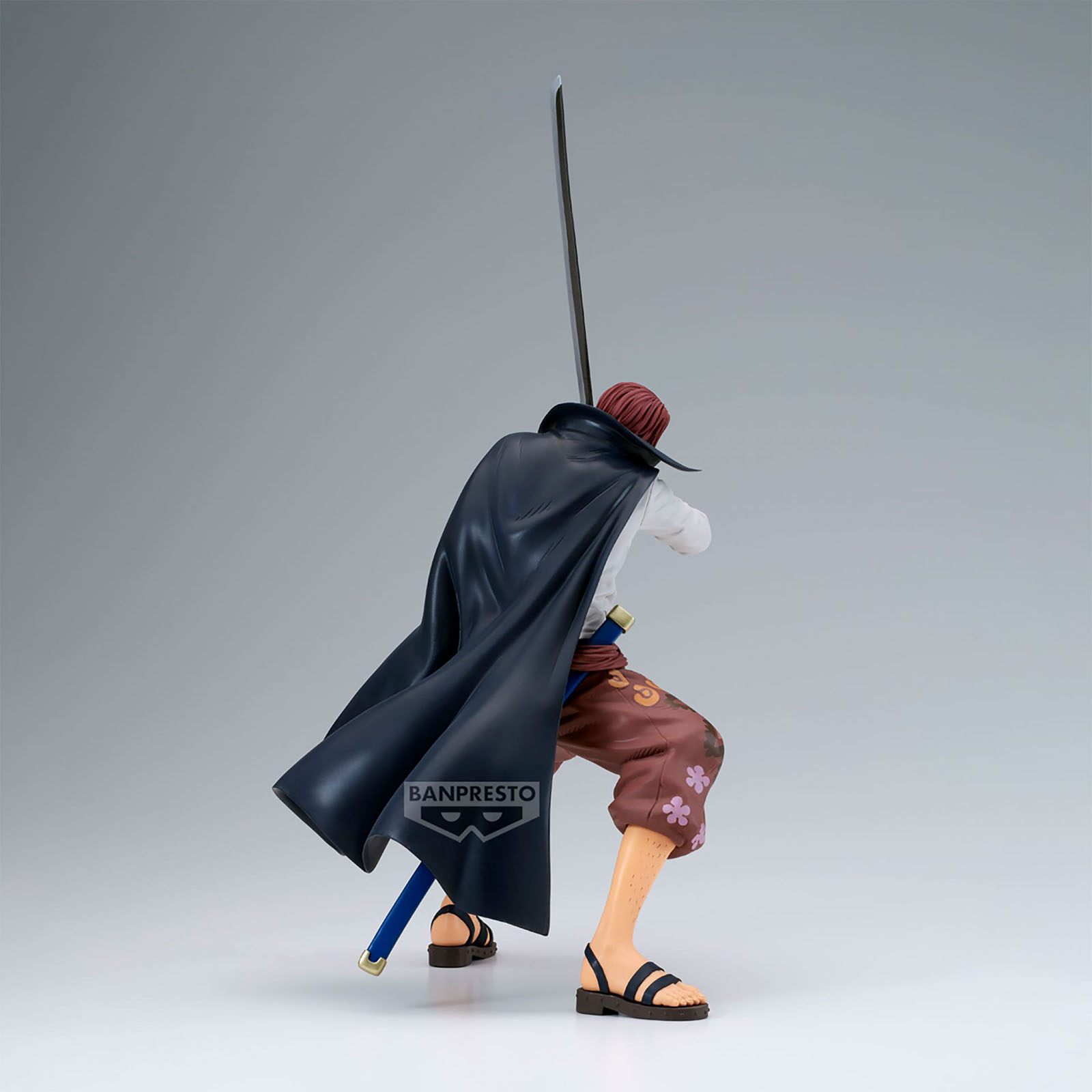 Eine Shanks-Figur mit Schwert, schwarzem Umhang und brauner Hose mit floralen Details. Er ist abgewandt.
