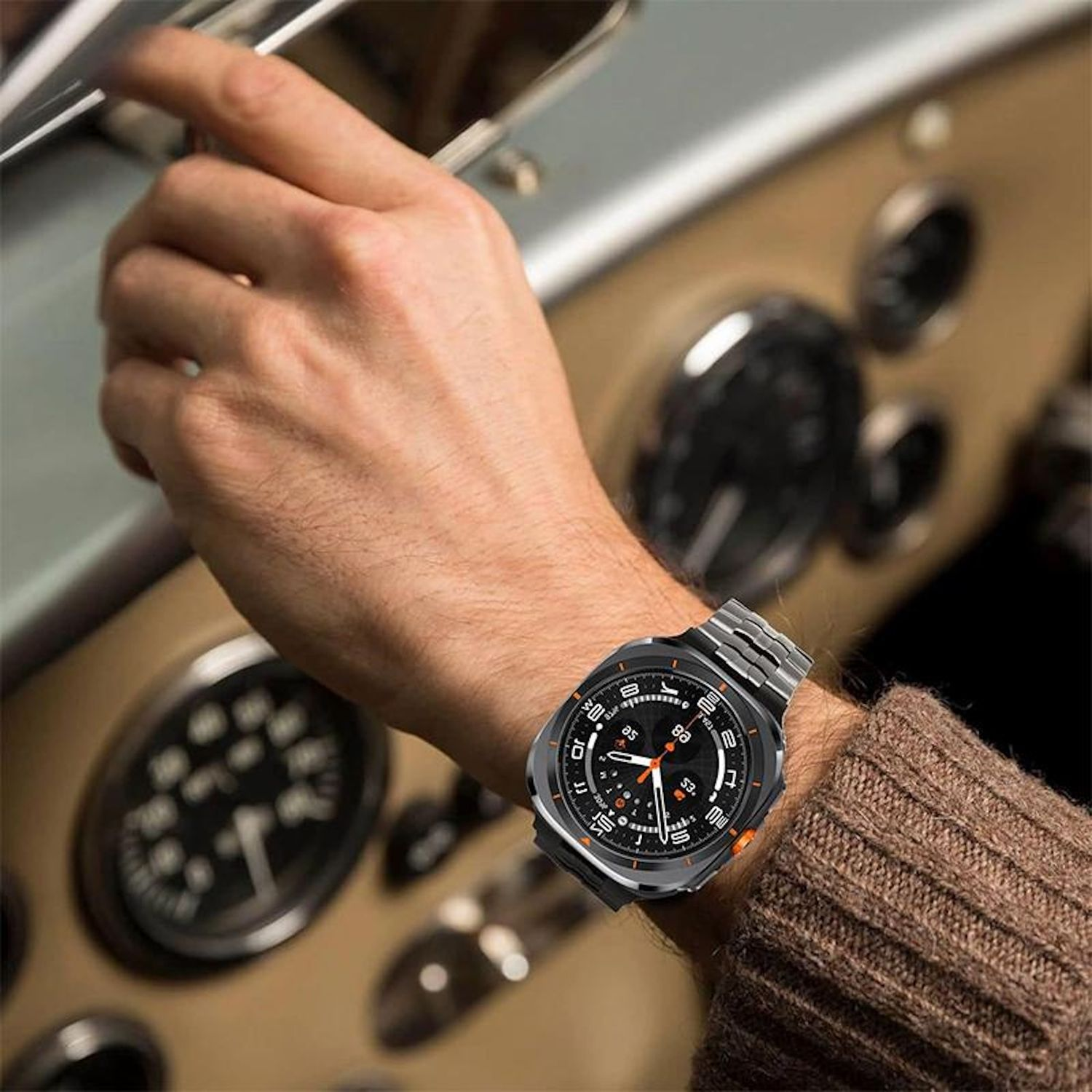 Eine Person in einem Auto, die eine Smartwatch trägt. Die Uhr befindet sich am Handgelenk. Die Hand ist am Lenkrad.