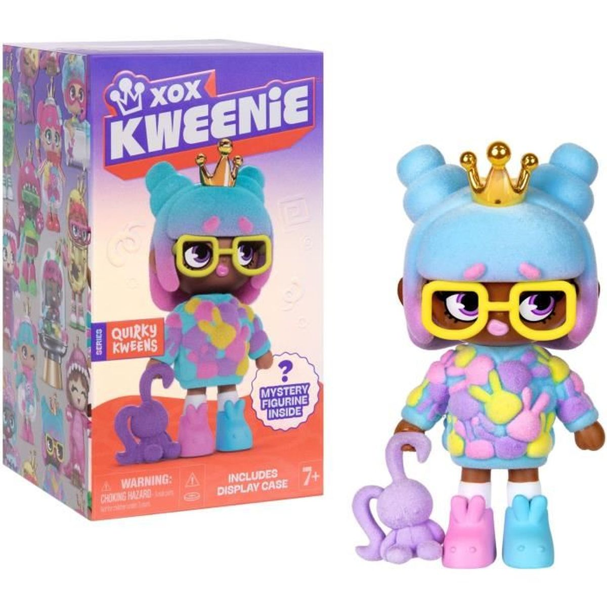 Eine Kweenie-Puppe mit Krone, Brille und bunter Kleidung sitzt neben ihrer Box. Zubehör: ein lila Hase und zwei bunte Schuhe.