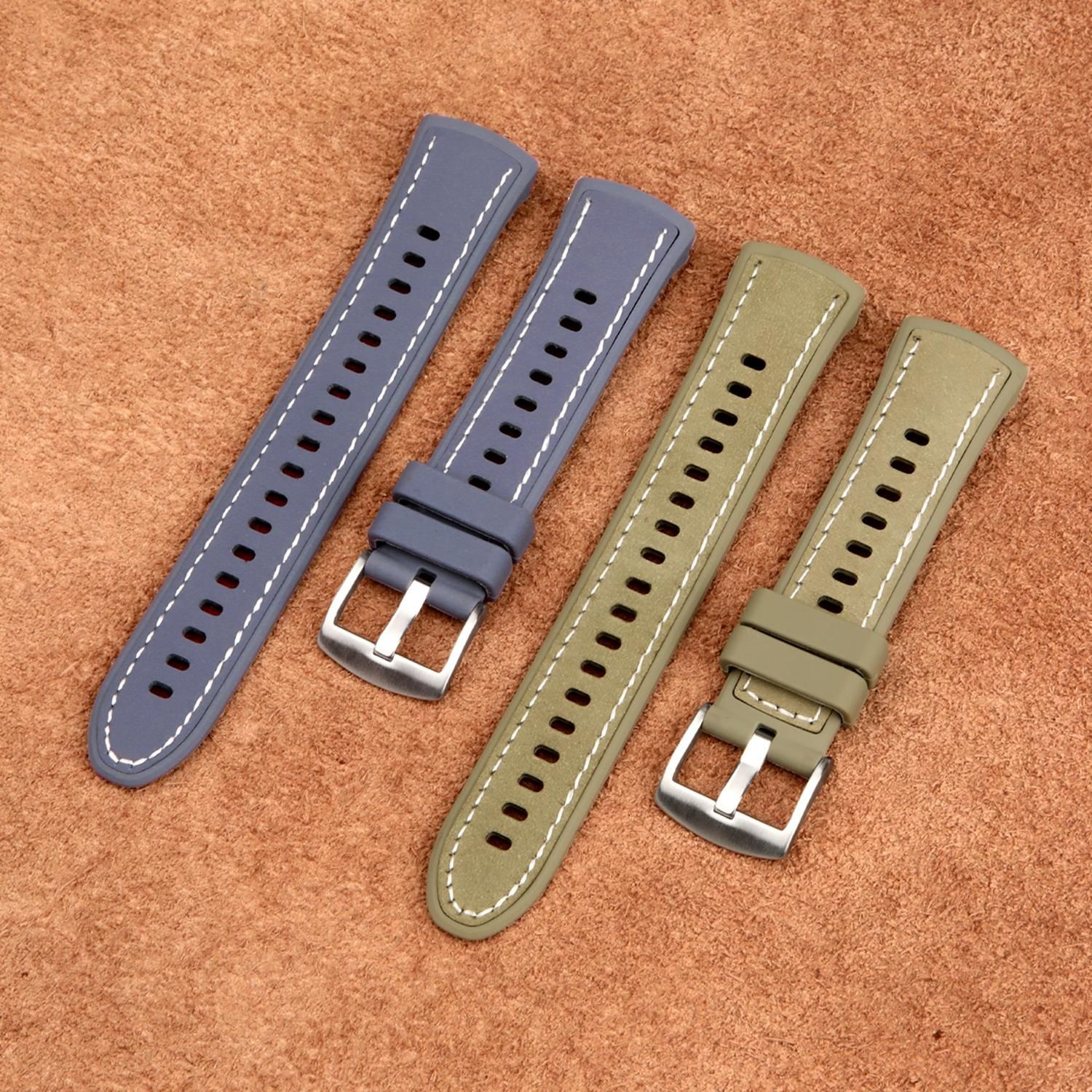 Vier Uhrenarmbänder in Blau und Olivgrün, angeordnet auf einer strukturierten braunen Oberfläche. Jeder Riemen hat eine Metallschnalle.
