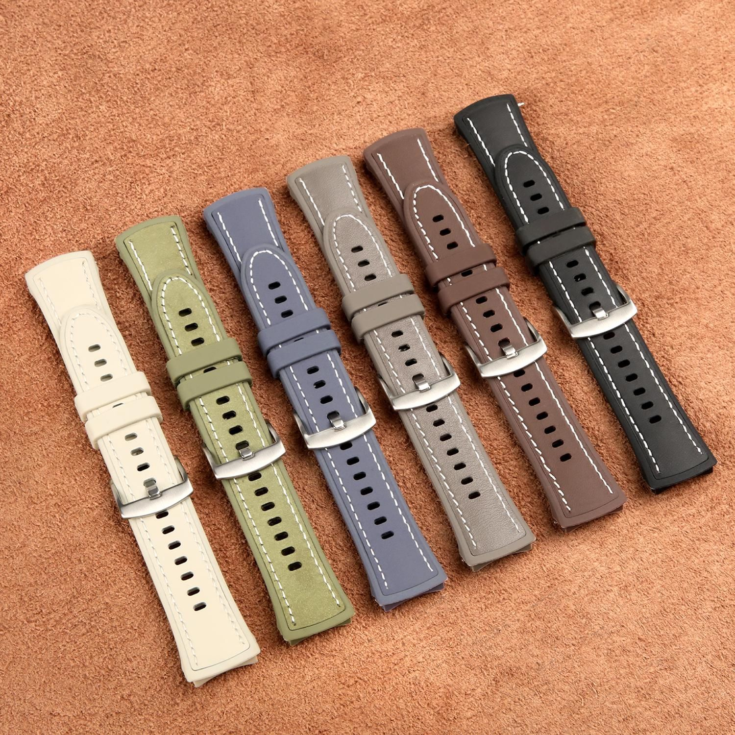 Sechs Armbänder in verschiedenen Farben (Beige, Grün, Blau, Grau, Braun, Schwarz) liegen auf einer braunen strukturierten Oberfläche.
