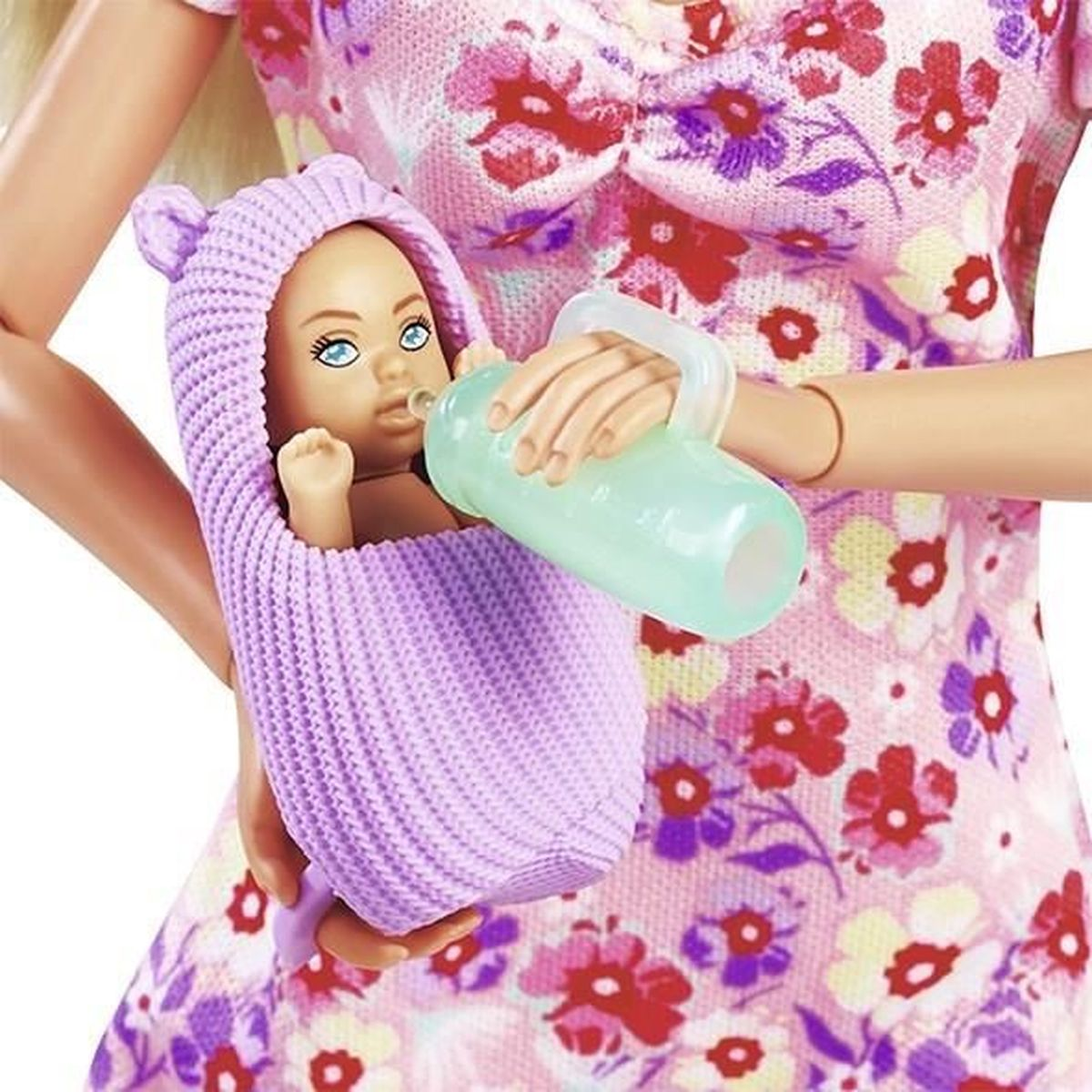 Eine Puppe füttert eine Babypuppe. Die Babypuppe befindet sich in einer lila Trage. Die Person trägt ein Blumenkleid.