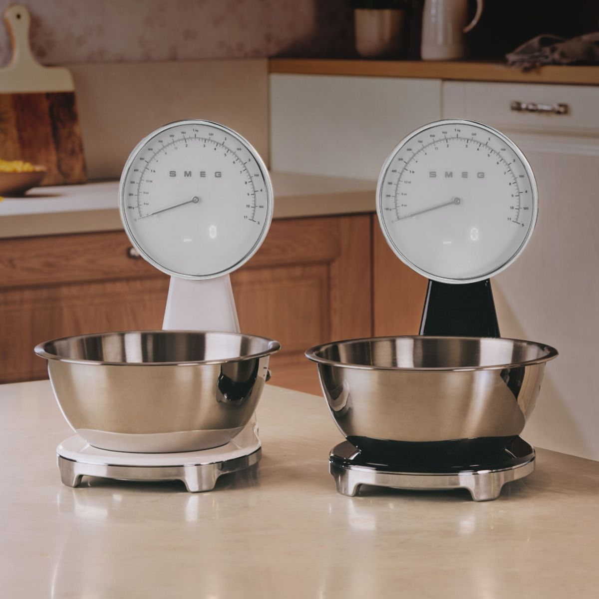 Dwie wagi SMEG z miskami na blacie. Jedna biała, druga czarna. Otoczenie kuchenne.