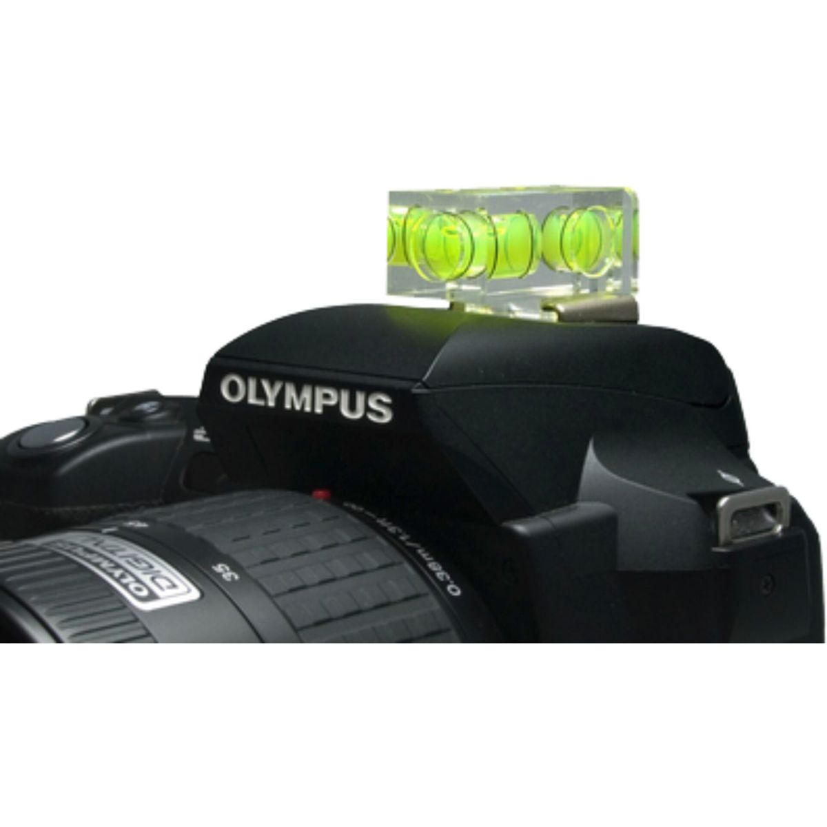 Czarny aparat Olympus z dołączoną poziomicą. Poziomica ma w środku zielony płyn. Obiektyw jest widoczny. Tło jest białe.
