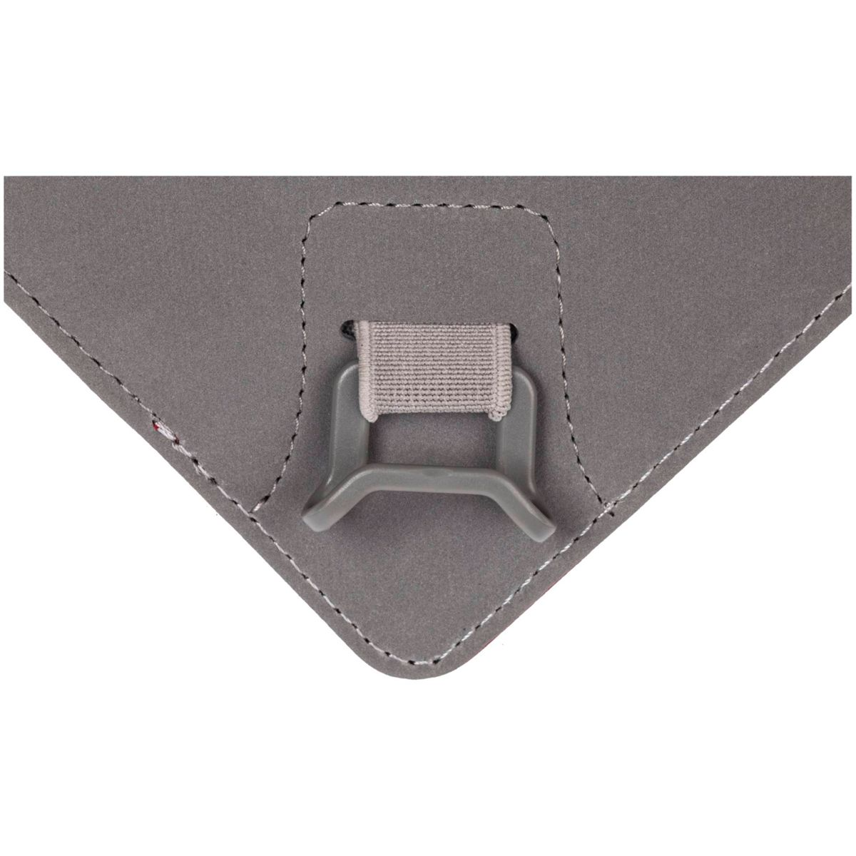 Primer plano de un objeto gris en forma de triángulo. Tiene un clip de plástico gris con una correa de tela adjunta, cosida al objeto.