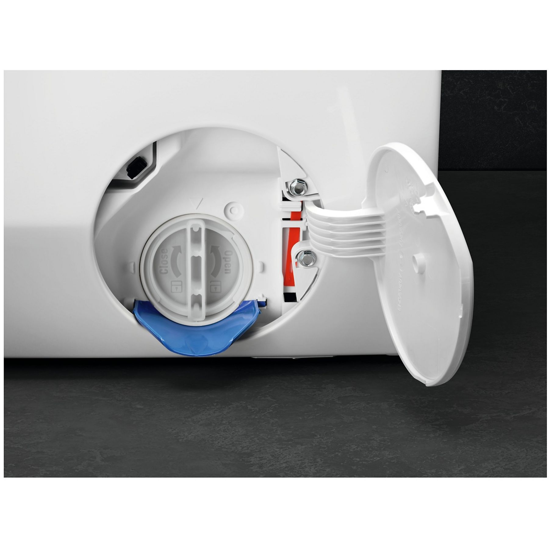 Cassetto detersivo lavatrice aperto. Plastica bianca con componenti blu, grigi e rossi. Superficie grigio scuro.